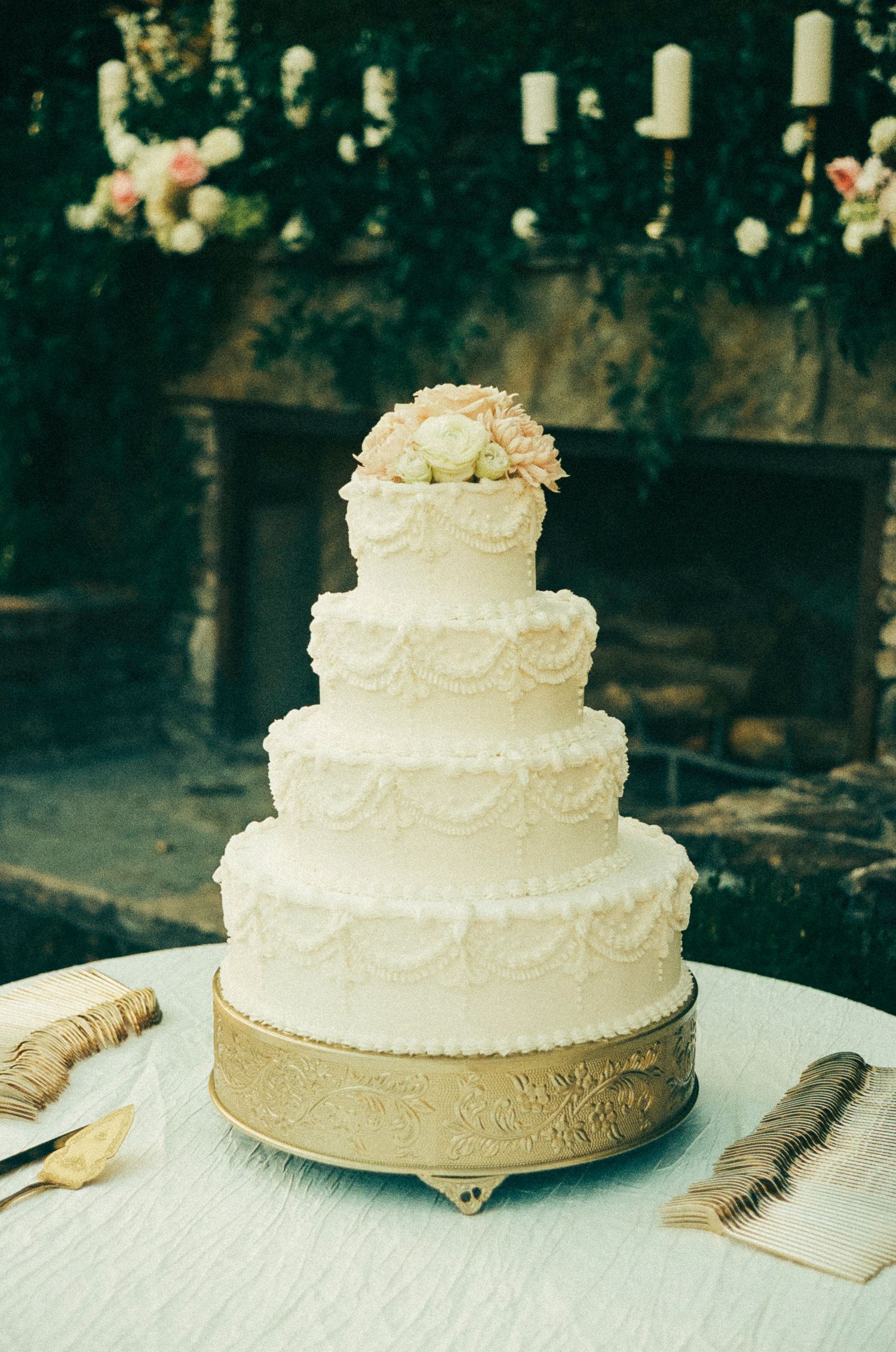 Four sequential photos show the progression of a classic white wedding cake being decorated with delicate piping and floral details.