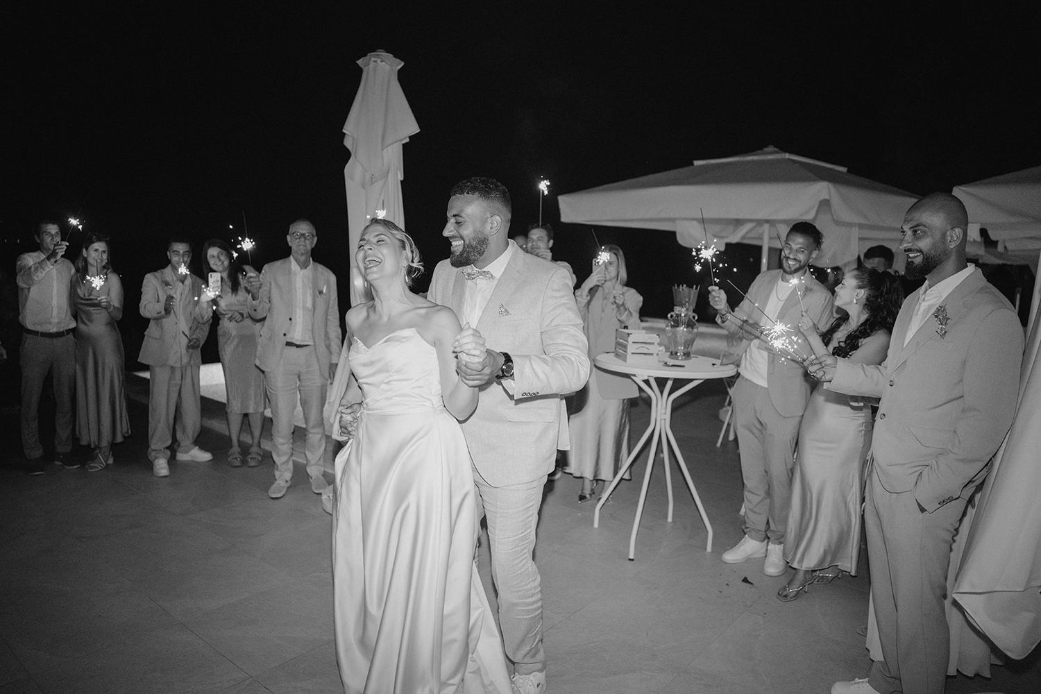Bride and groom share their first dance surrounded by guests at an outdoor nighttime wedding reception.