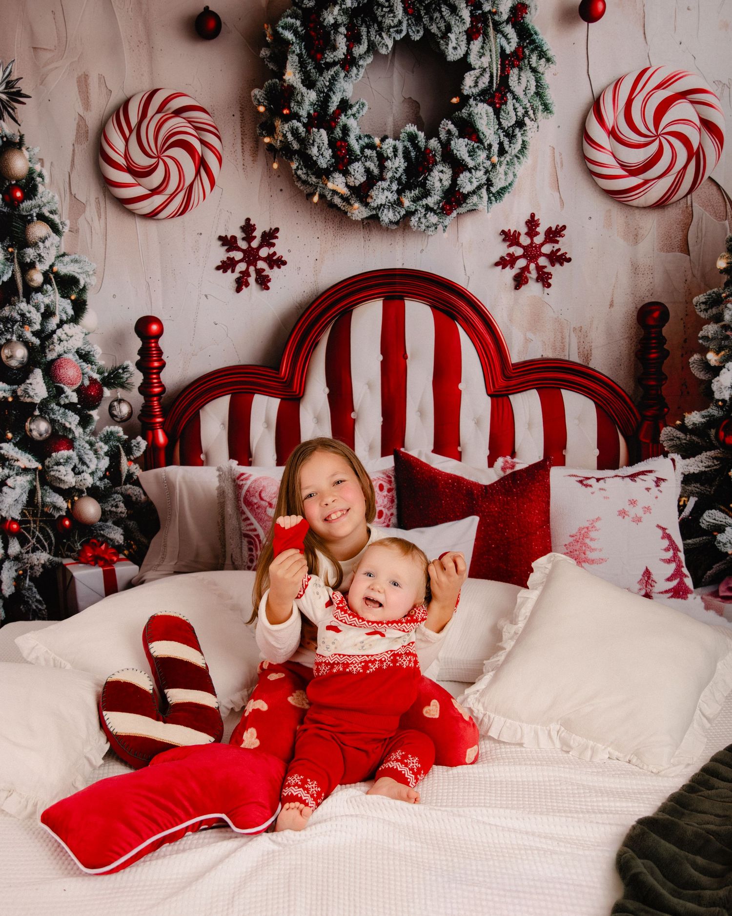 A festive holiday photo session with red and white striped decorations, peppermint candies, and greenery garlands.