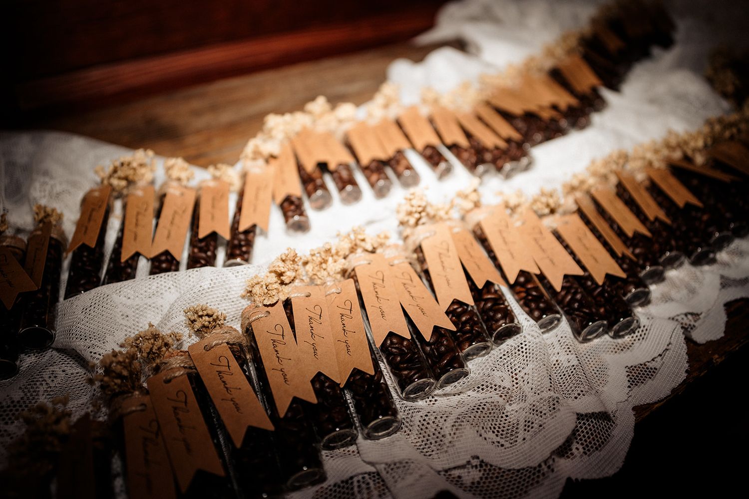 Elegant wedding place cards with wooden clips displayed on white lace with floral decorations.