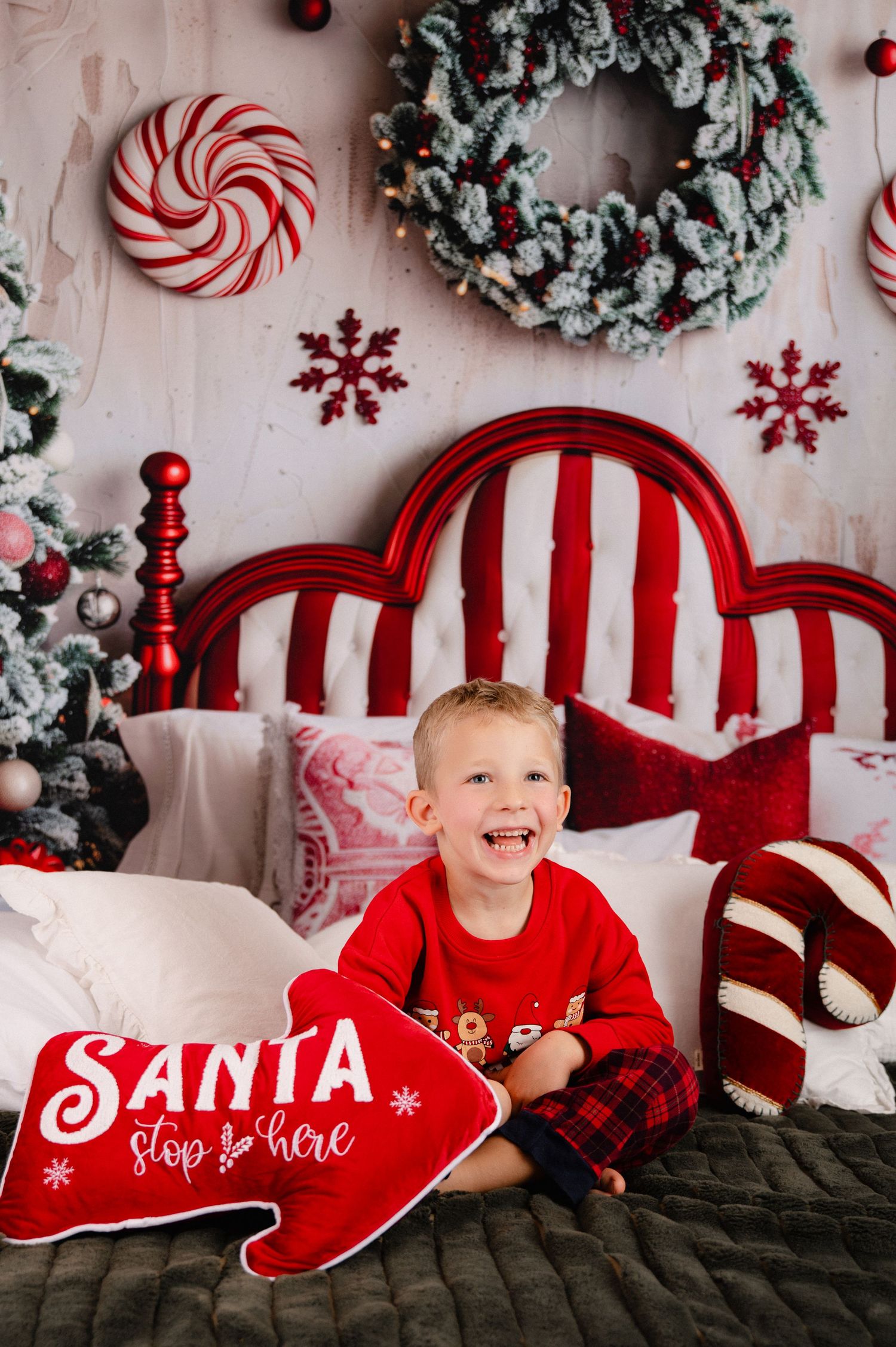 Christmas themed bedroom decor with red headboard, peppermint decorations, wreath and Santa stop here sign on bed.