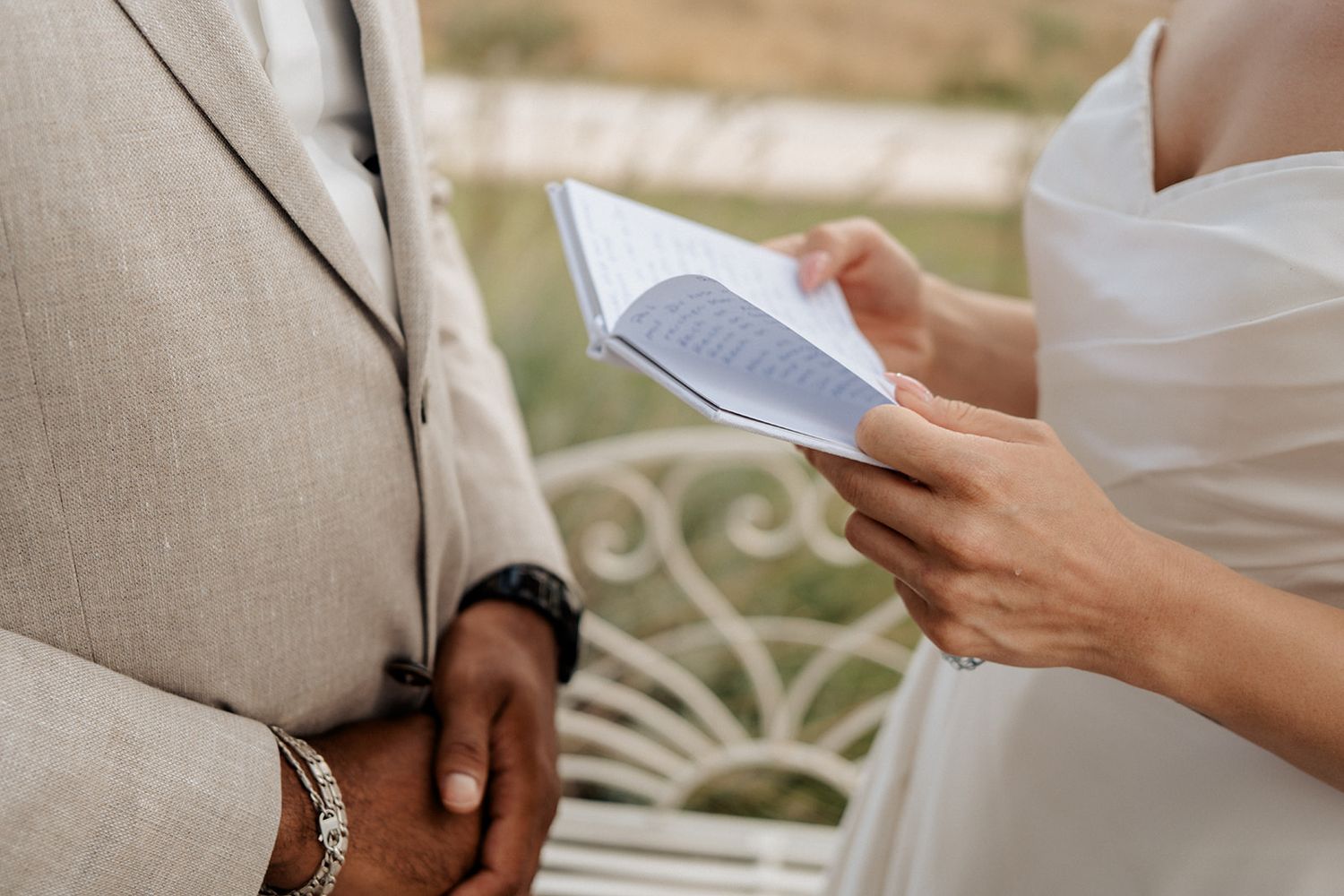Two people reviewing a document together outdoors, one wearing a beige blazer and the other in white attire.