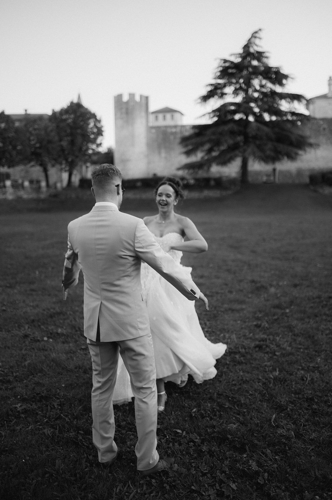 Black and white photo of bride and groom dancing in castle grounds at dusk.