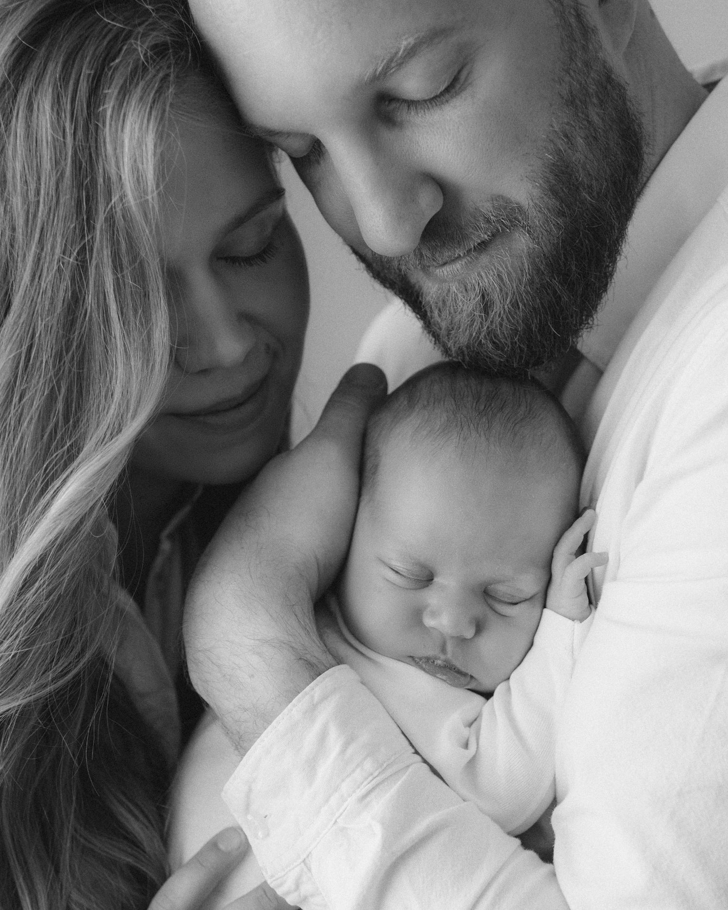 A series of five intimate black and white portraits showing tender family moments with parents and their newborn baby.