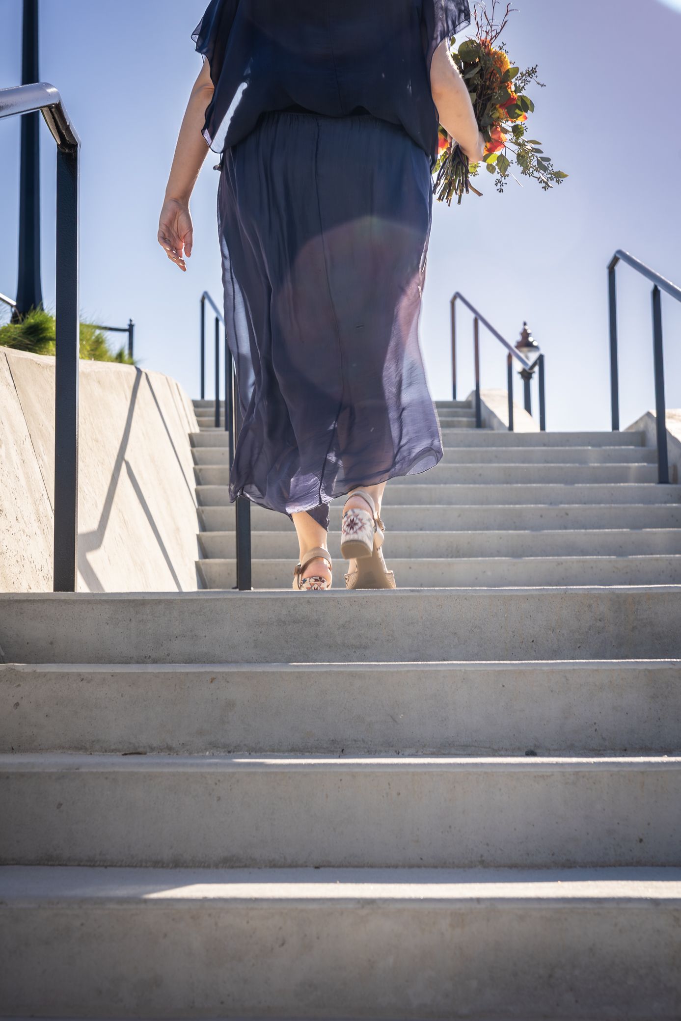 Low angle view of wedding couple's feet descending concrete steps outdoors.