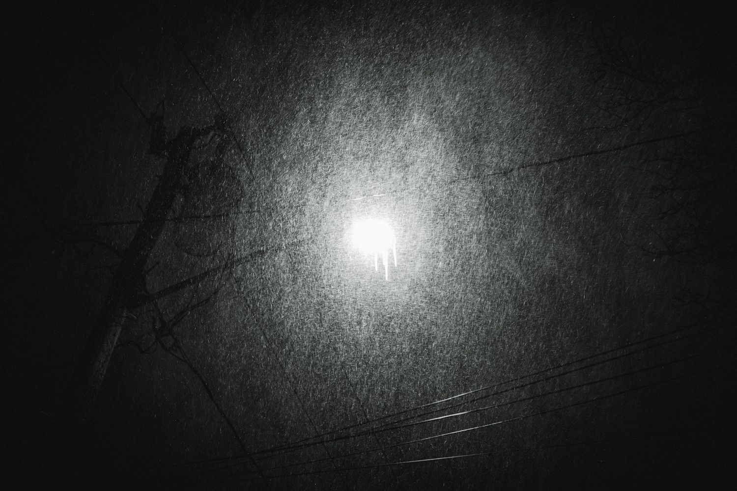 A bright light source illuminates a dark misty night sky creating an ethereal glow through fog.