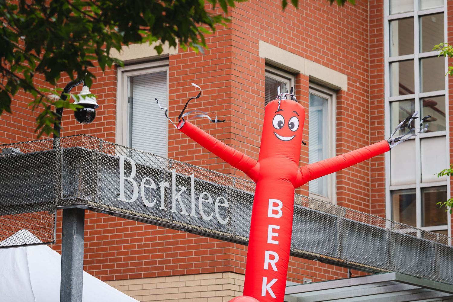 Red inflatable tube man dancer in front of Berklee College of Music brick building sign in Boston.