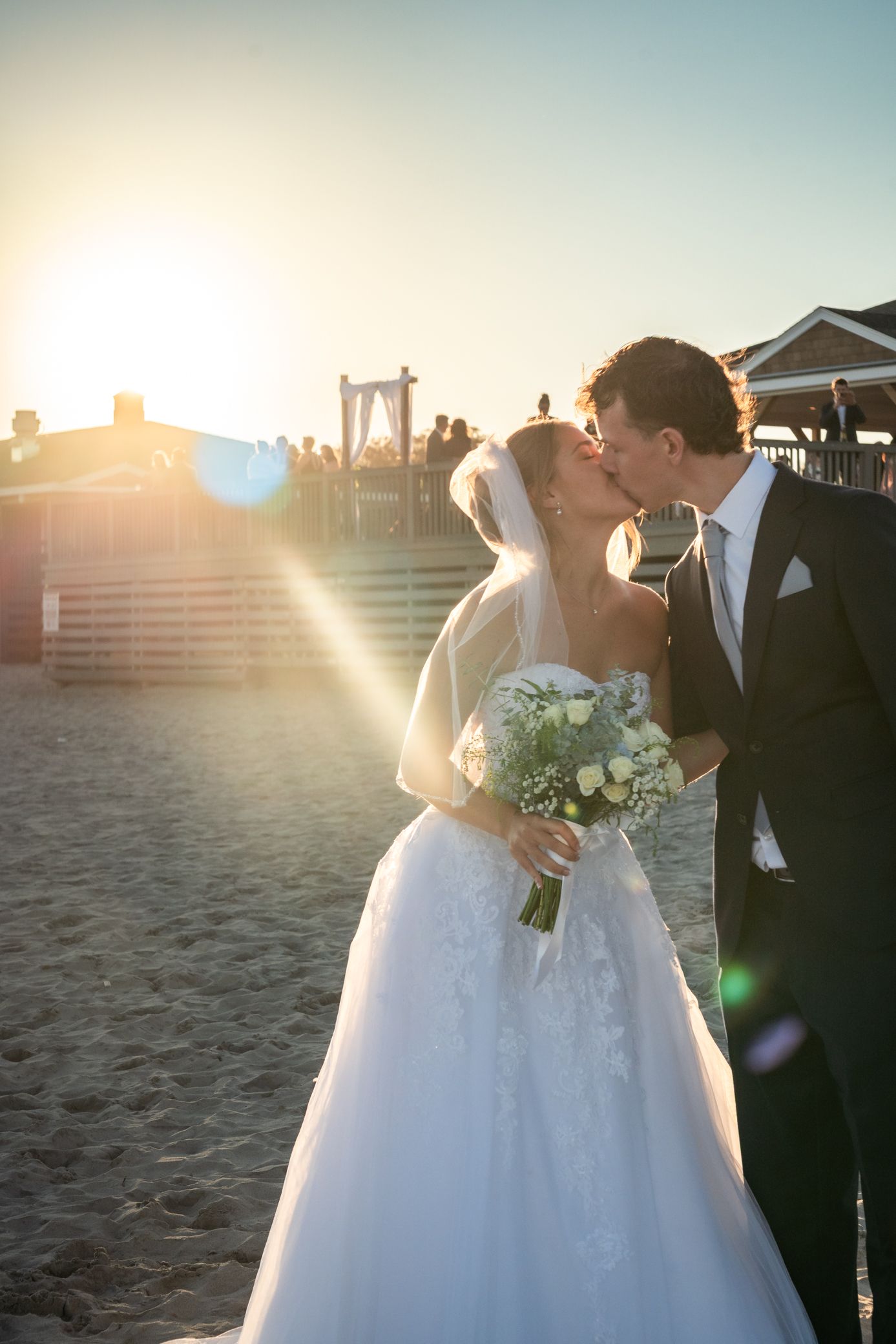 A romantic beach wedding ceremony at sunset with the couple sharing a tender moment.