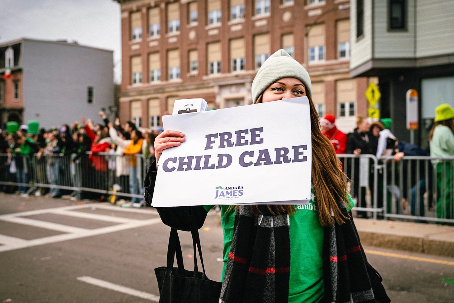 Protesters gather on a city street holding signs advocating for free childcare and other social causes.