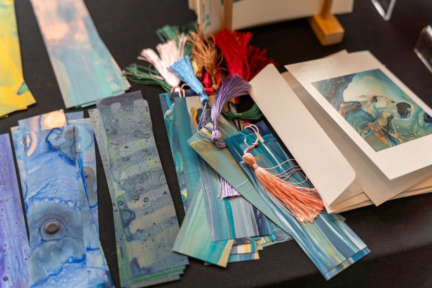 A collection of colorful artwork and paintings displayed on a dark surface, showcasing various artistic styles and mediums.
