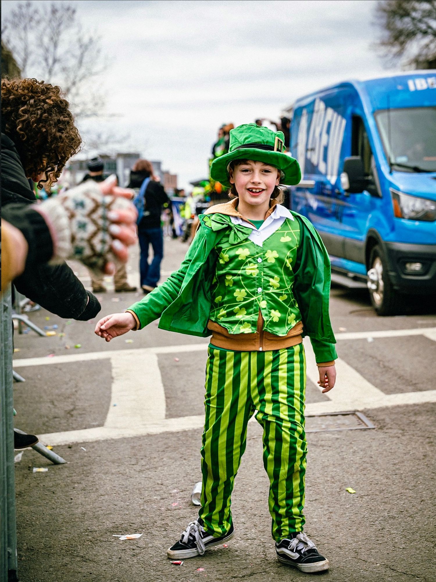 A series of photos showing someone in a festive green striped outfit celebrating St. Patrick's Day in a parking lot.