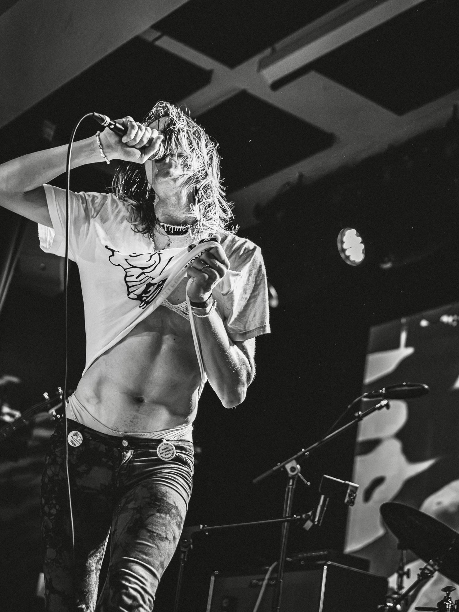 Black and white photo of a rock singer performing on stage, holding a microphone with midriff exposed.