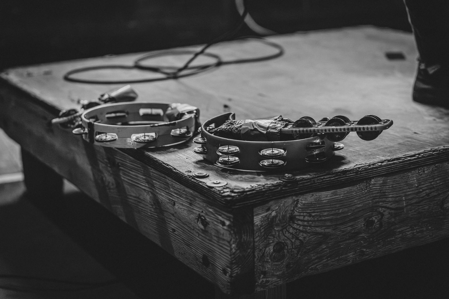 Two tambourines resting on a wooden platform in black and white photography at local music venue and dive bar, Allston's Silhouette Lounge.