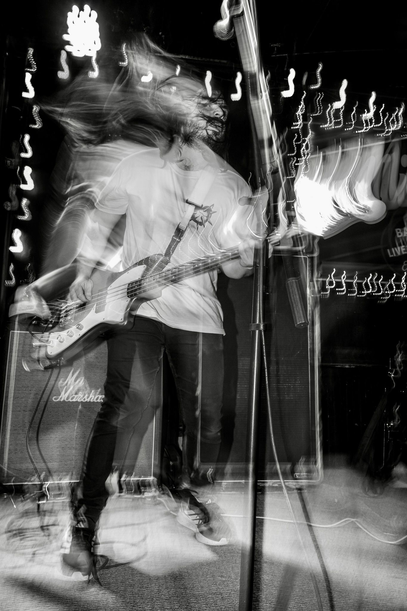 Black and white motion blur photography captures dancers moving energetically on a stage with musical notes in background.