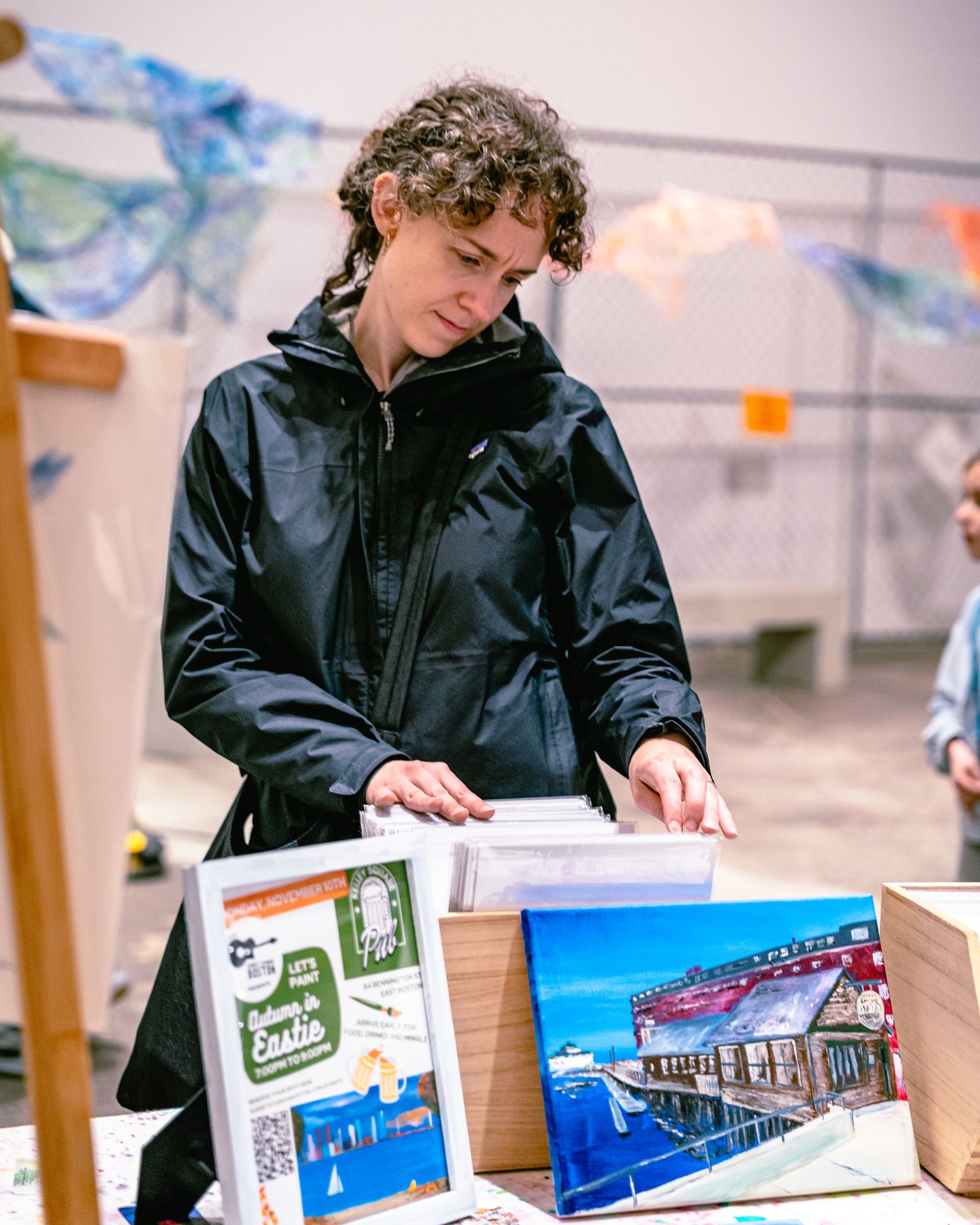 Student examining architectural model displays and printed materials showing building designs and layouts.