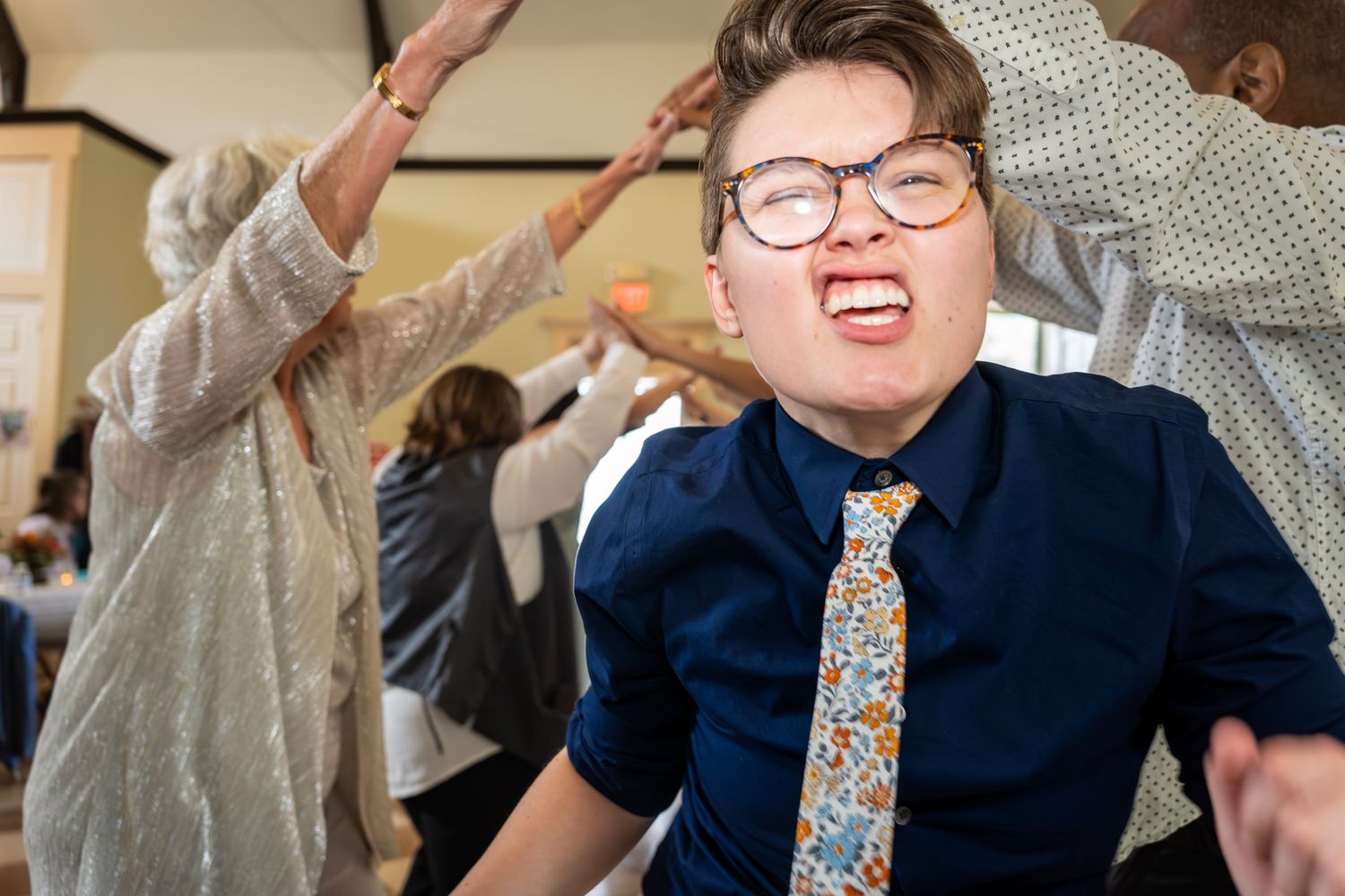 A group of people dancing and celebrating at a lively indoor party with joyful expressions.