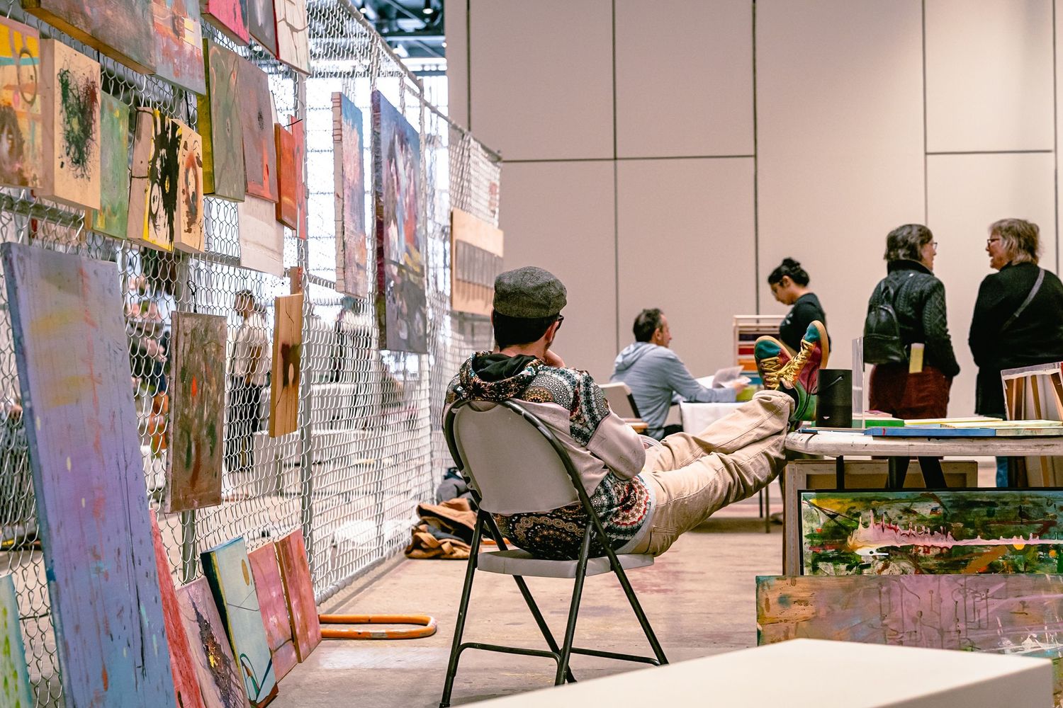 Students collaborate at tables in a modern classroom with colorful artwork displayed on the walls.