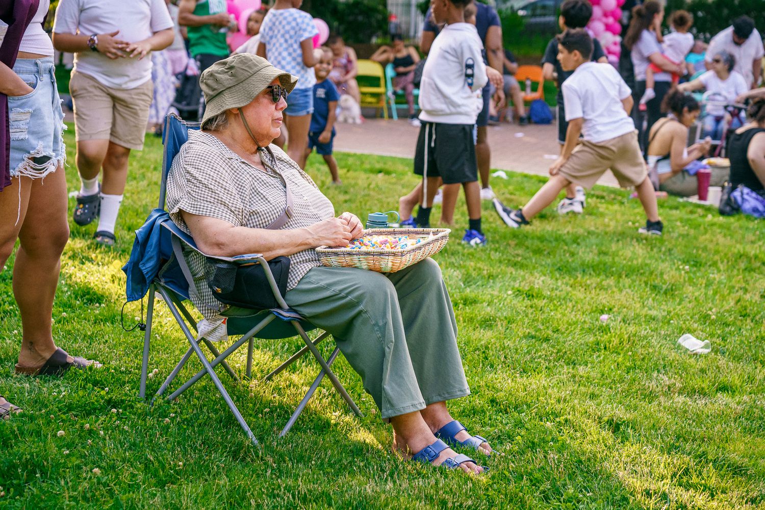 Crowd of people sitting in lawn chairs on grass during an outdoor summer event.