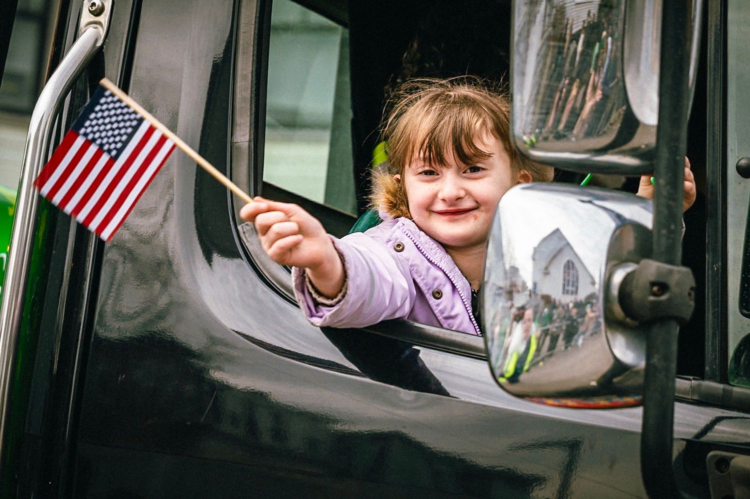 Students wave American flags through school bus windows during a patriotic celebration or parade.
