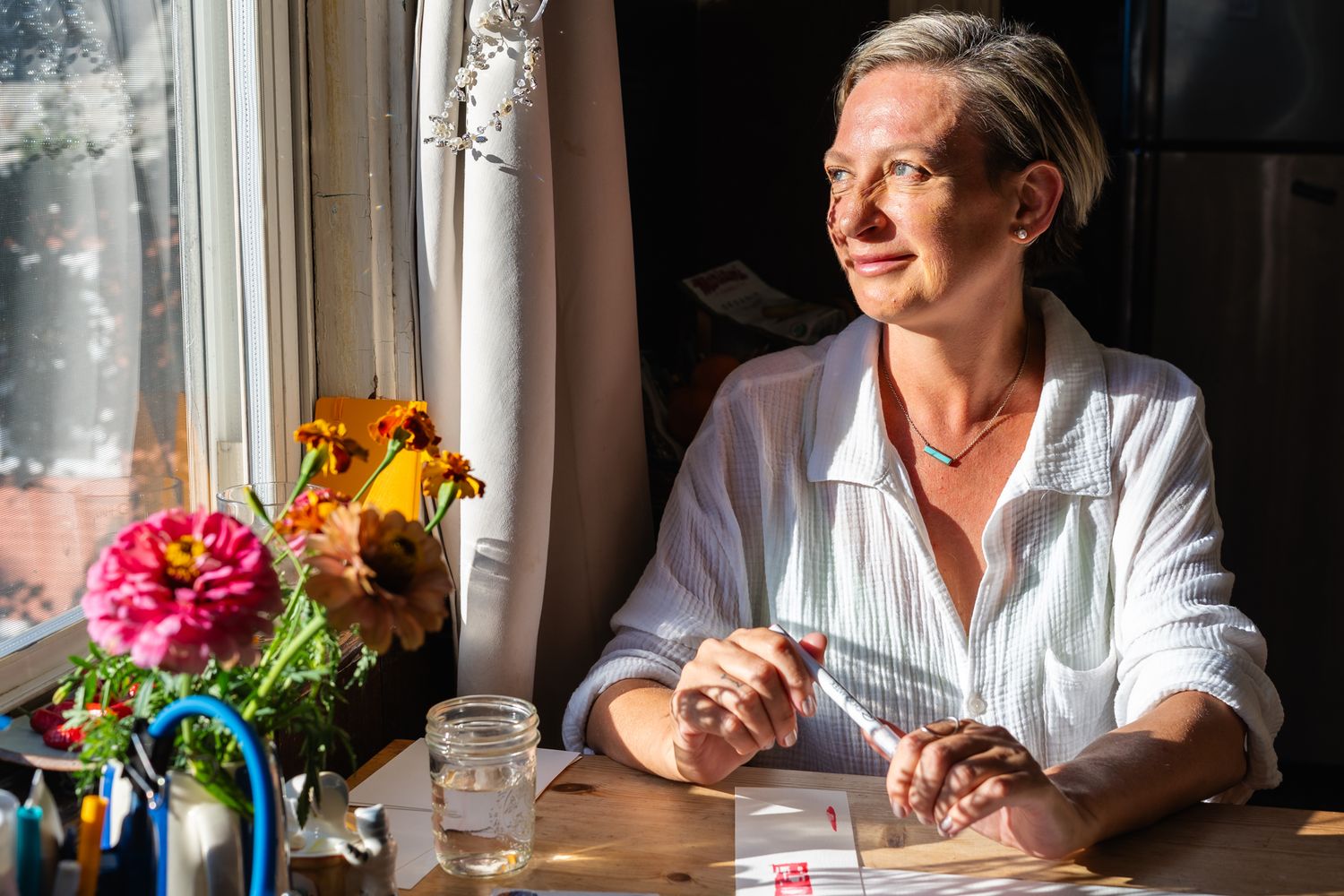 A person in a white shirt sits by a window in a series of connected photos with natural lighting and flowers.