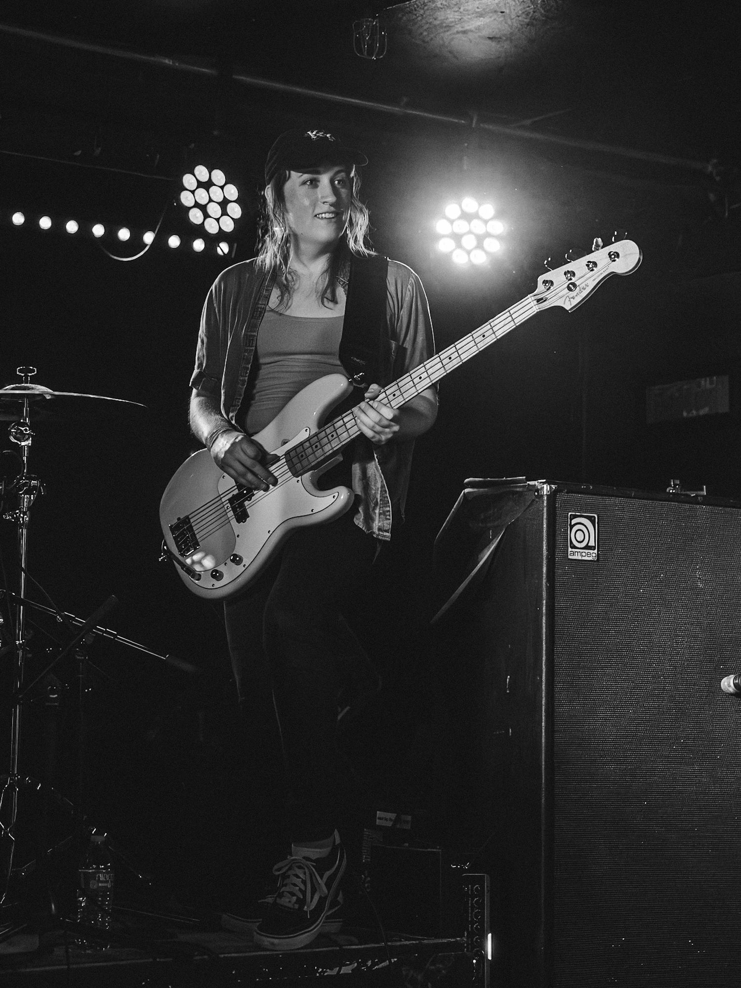 Woman playing electric bass guitar on stage in black and white live concert photo with stage lights.  (Band: Direct Hit!)