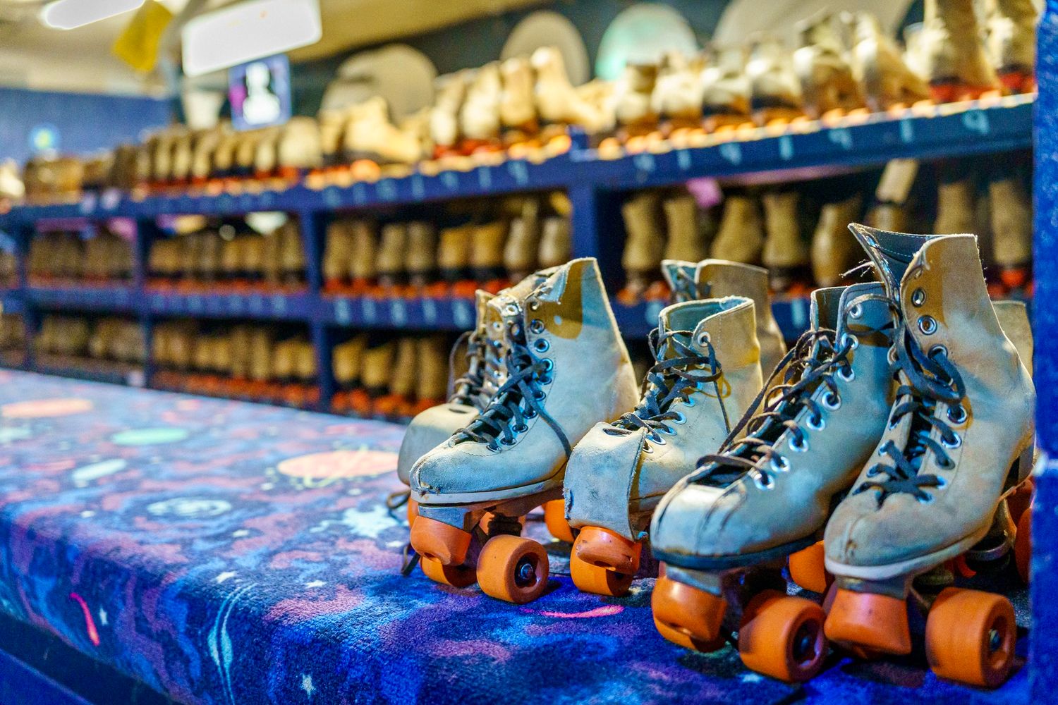 Vintage blue roller skates lined up on display at a retro skating rink rental counter.