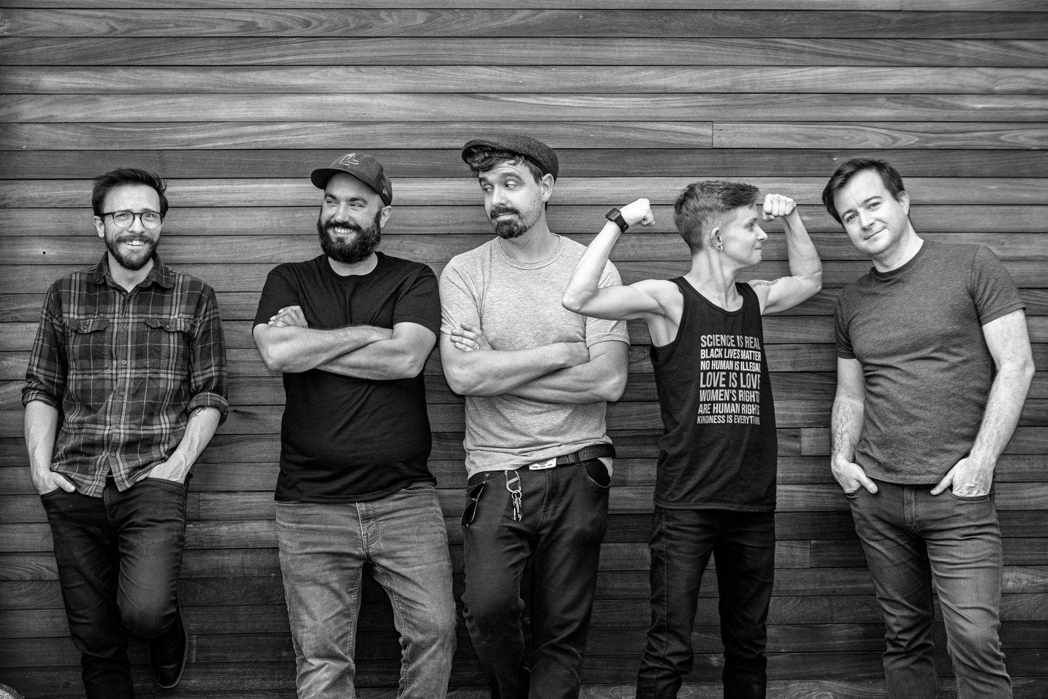 A series of black and white portraits showing people standing against a rustic wooden wall.