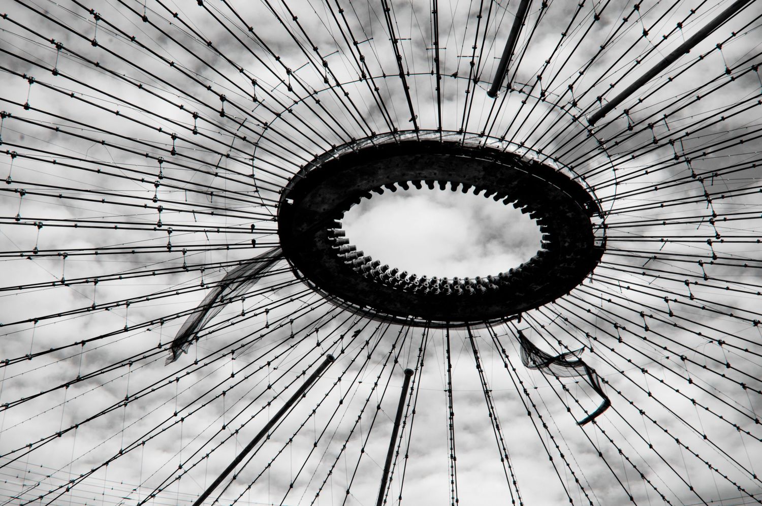 Black and white architectural abstract of a circular skylight with radiating metal beams creating a striking geometric pattern.
