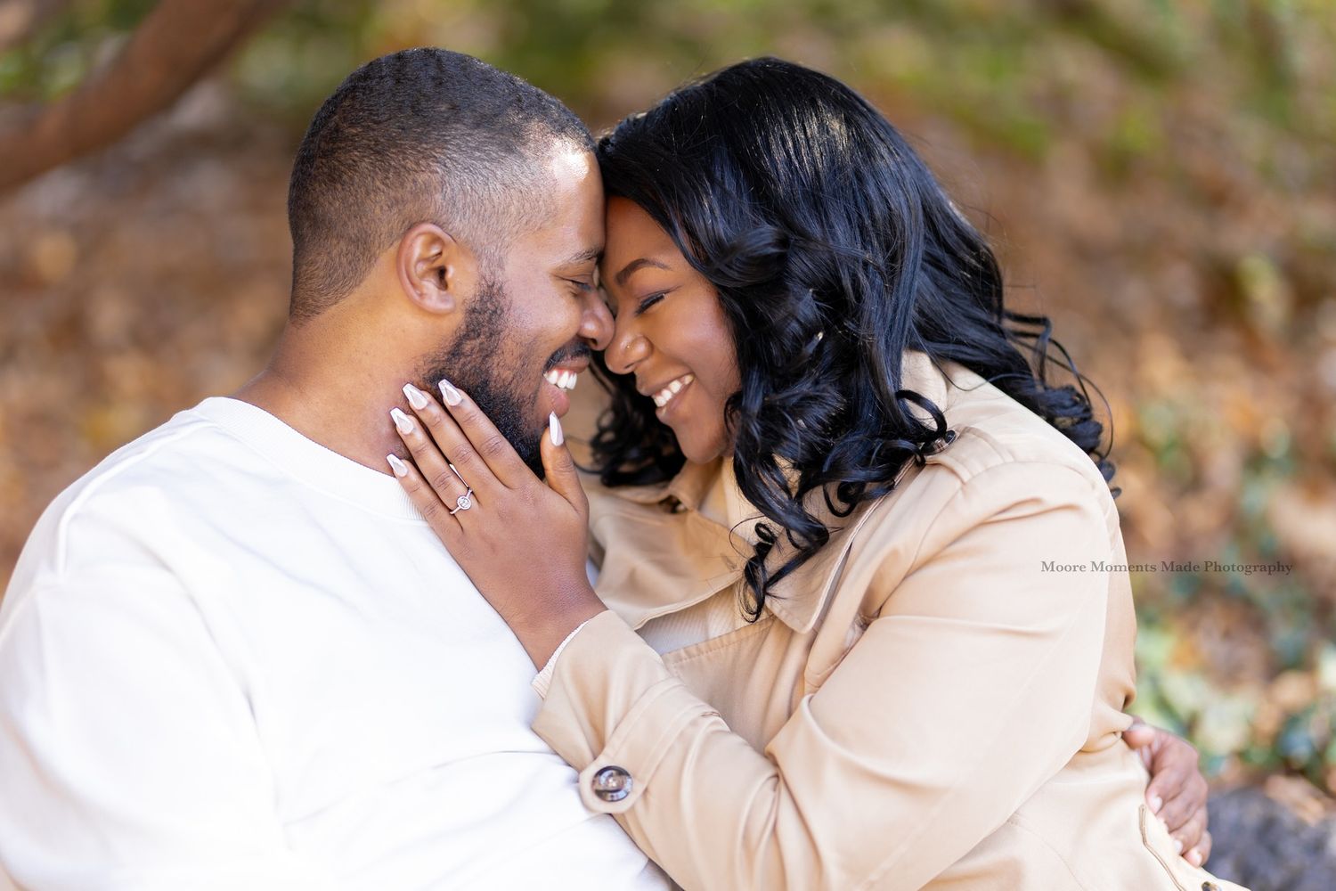 A tender engagement photo with a couple sharing an intimate moment against a fall backdrop.