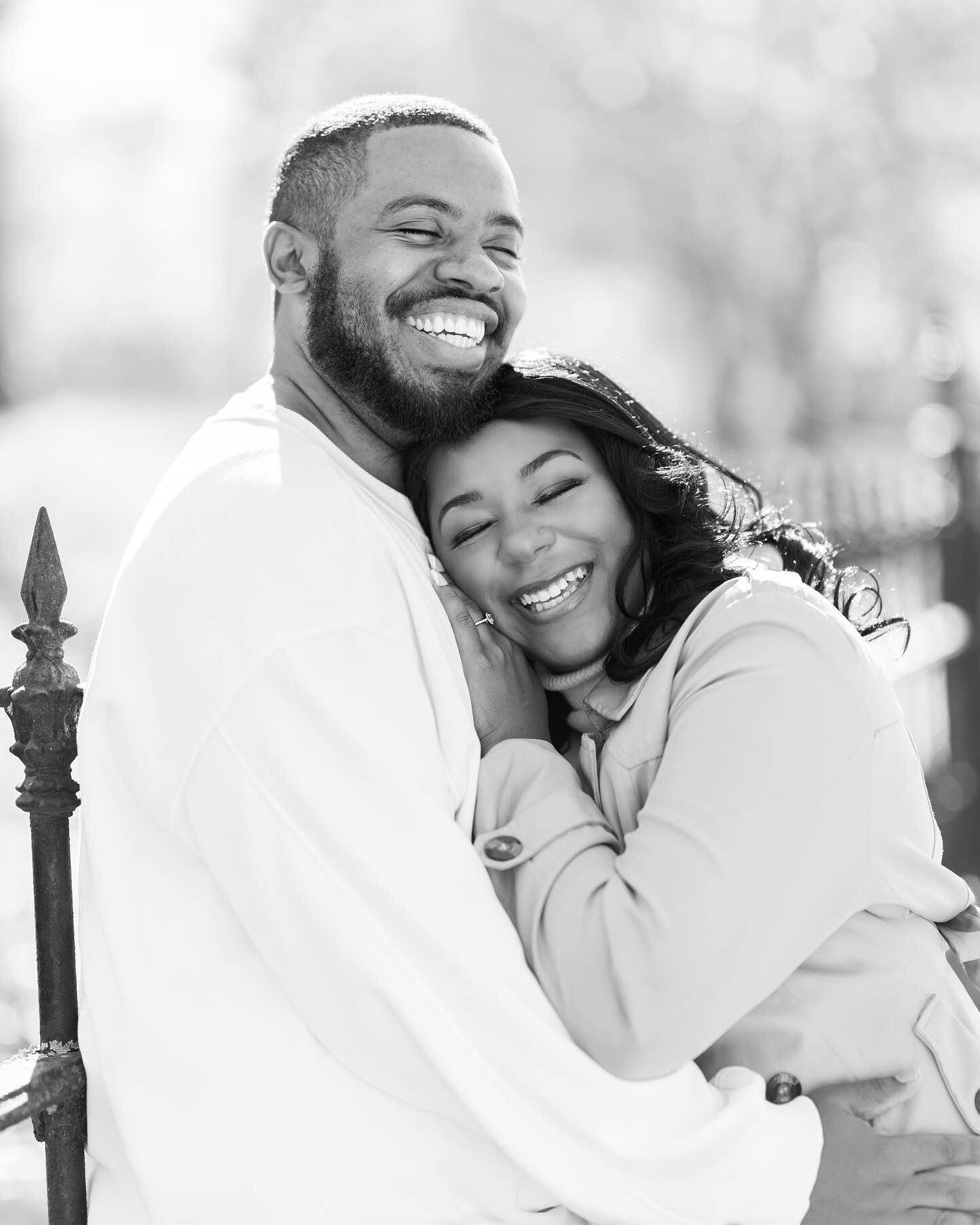 A joyful couple in white sweaters sharing a warm embrace outdoors.