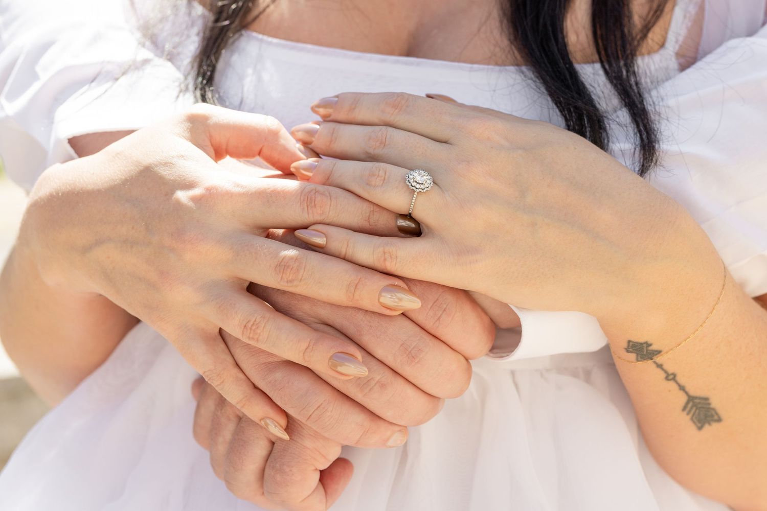 Close-up of hands showing an engagement ring with a small tattoo visible.