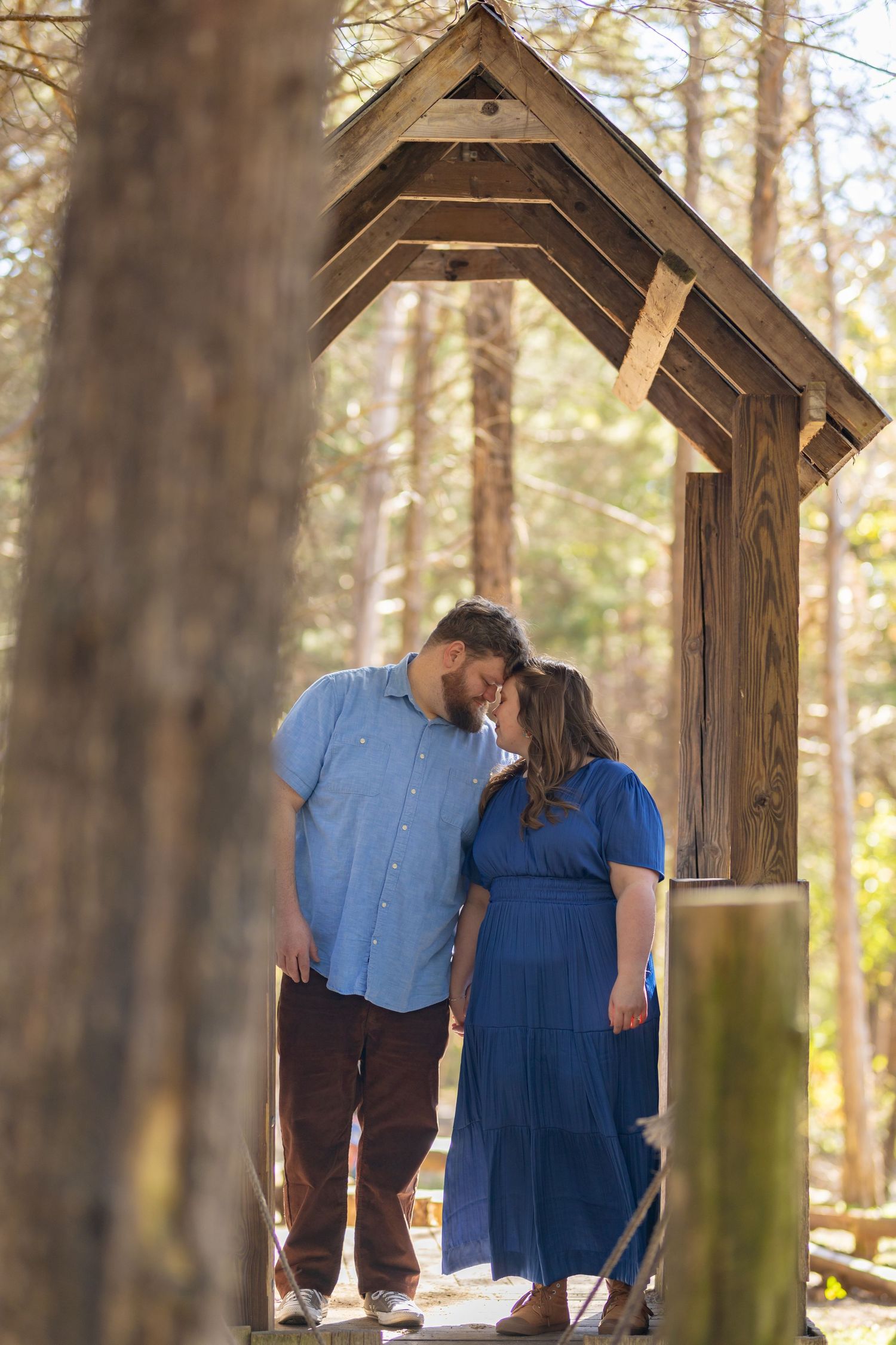 Romance under a rustic wooden gazebo in a sunlit forest setting.
