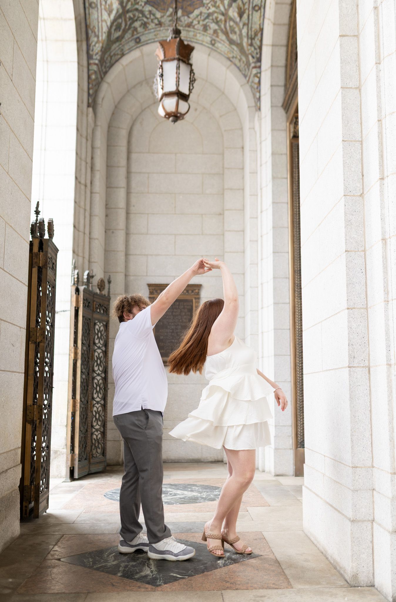 A couple dances together under an ornate archway with decorative lanterns.