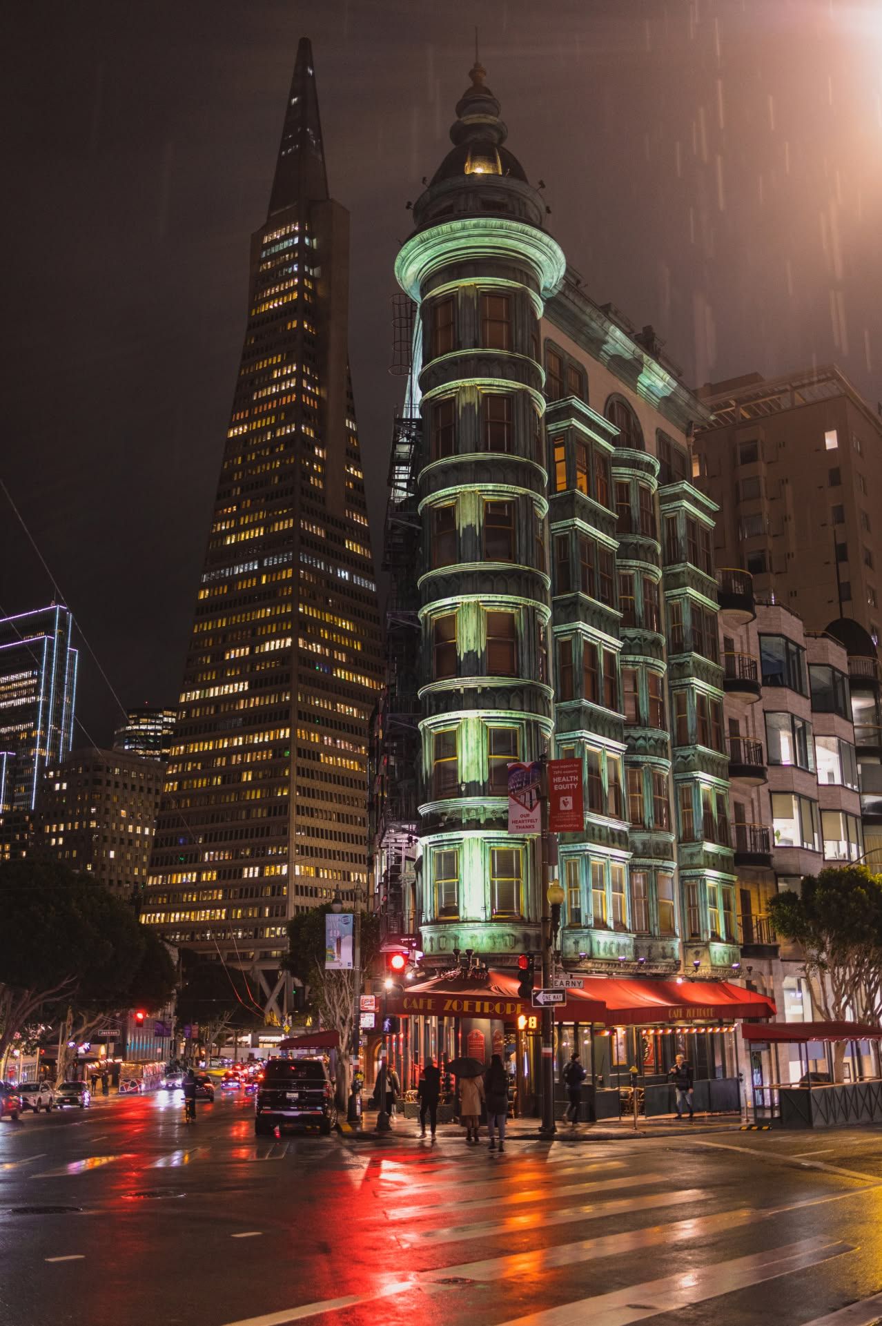 Transamerica Pyramid and Columbus Tower illuminated at night in rainy San Francisco.