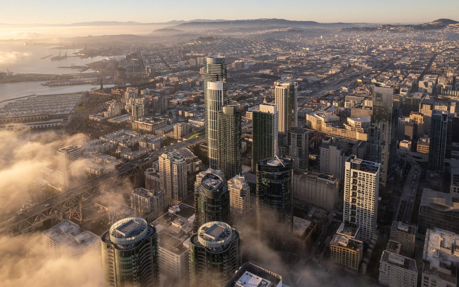 Aerial view of San Francisco skyline with skyscrapers emerging through morning fog layers.