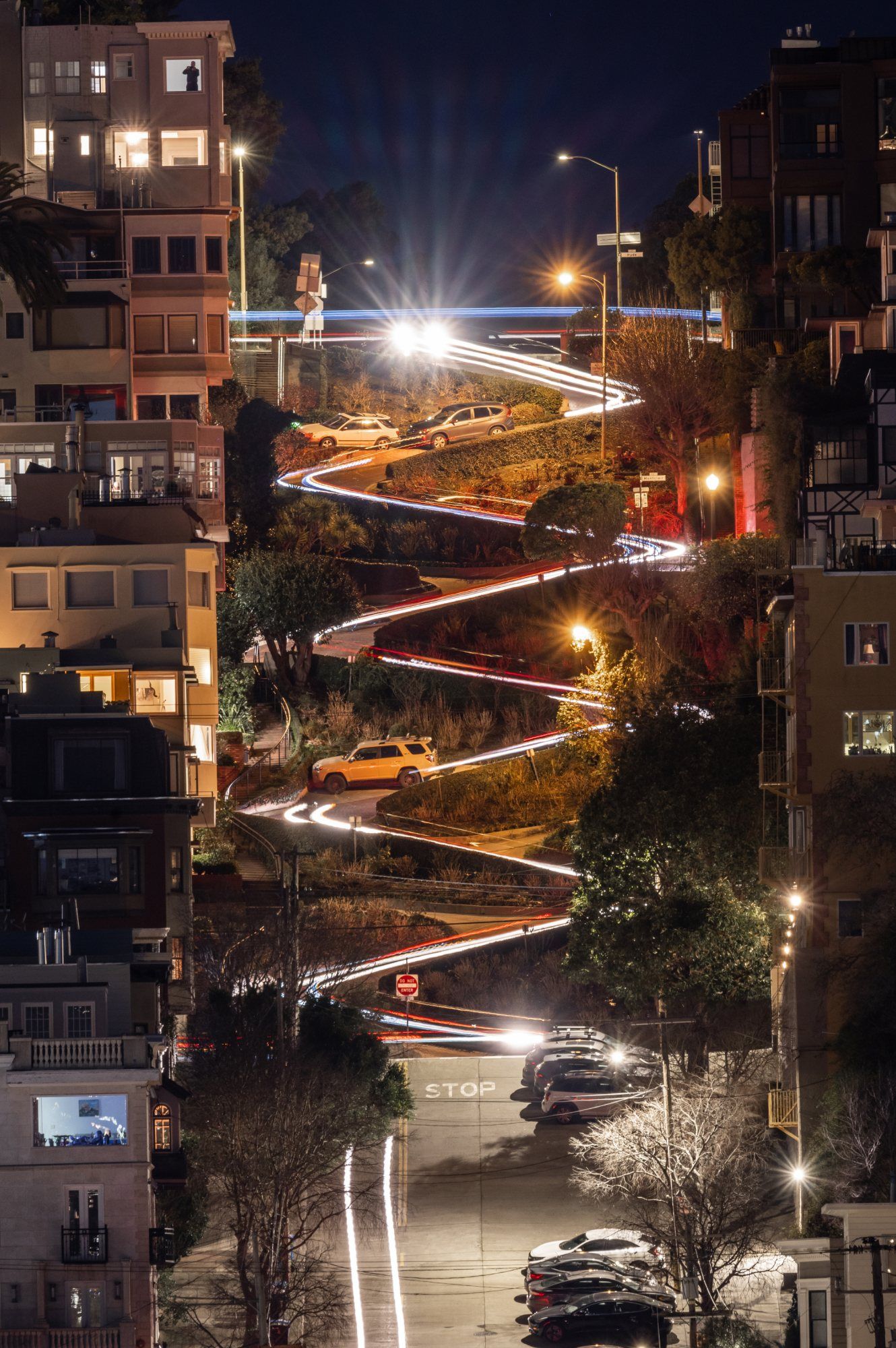 Long exposure night photography of Lombard Street winding curves with colorful car light trails in San Francisco.