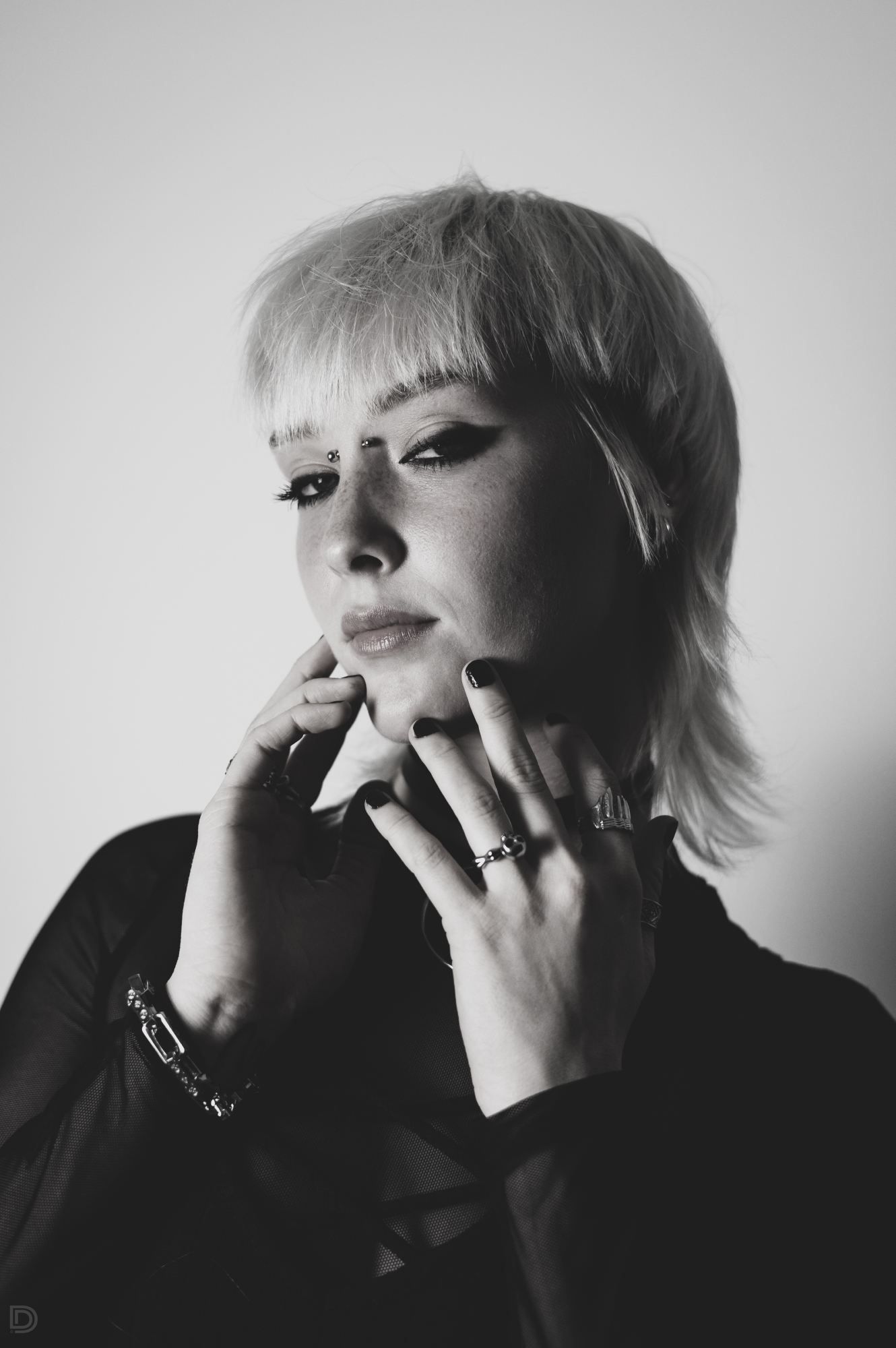 Black and white portrait of a woman with short blonde hair and dark nails in a gothic style.