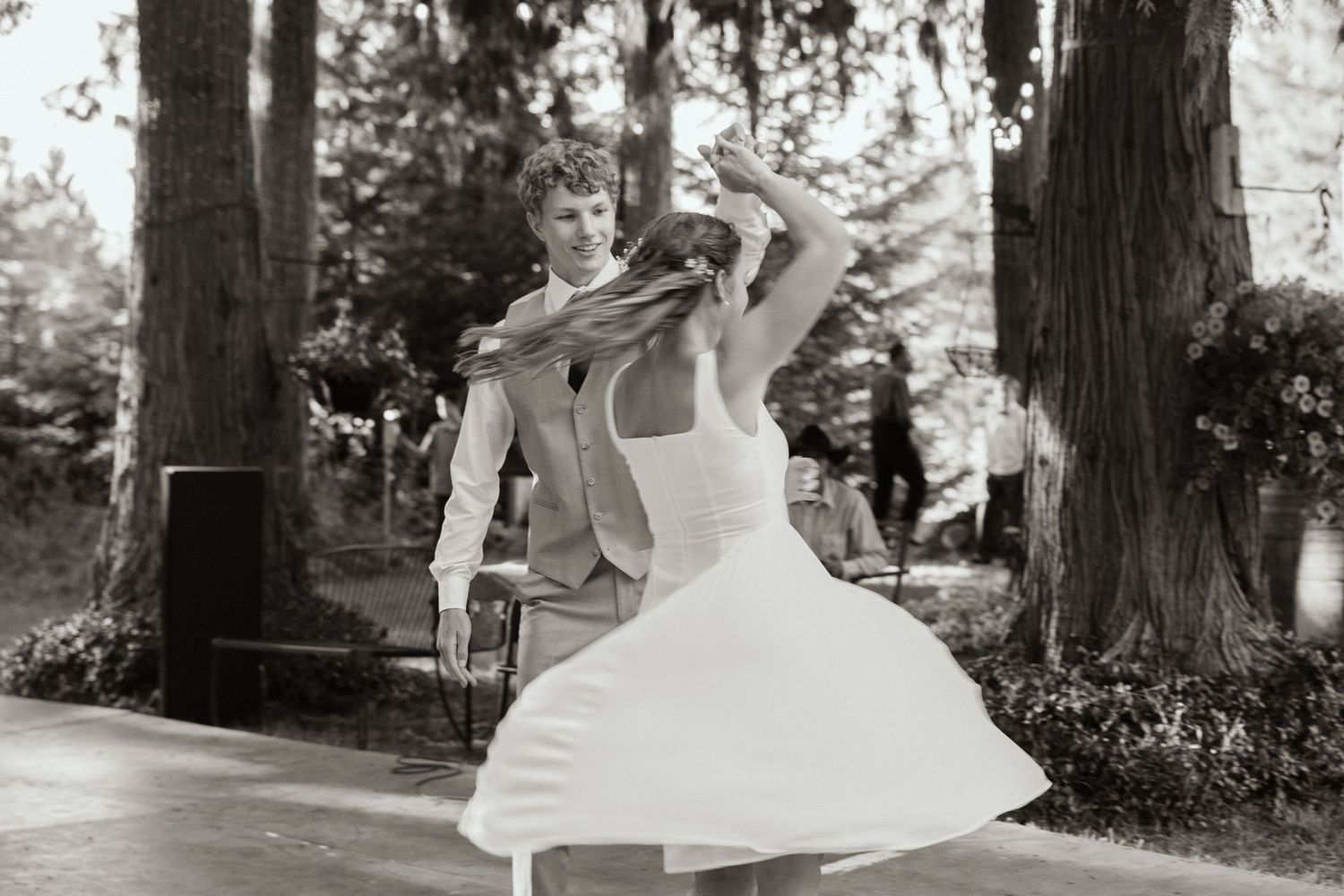 Black-and-white image of a bride and groom's first dance. The bride is spinning around, her dress flowing around her. A timeless moment.