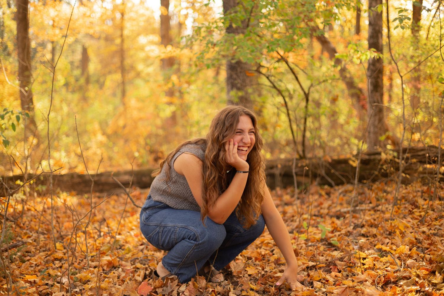 Happy young woman laughing in an autumn forest, surrounded by golden leaves, capturing warmth, happiness, and the beauty of the season.