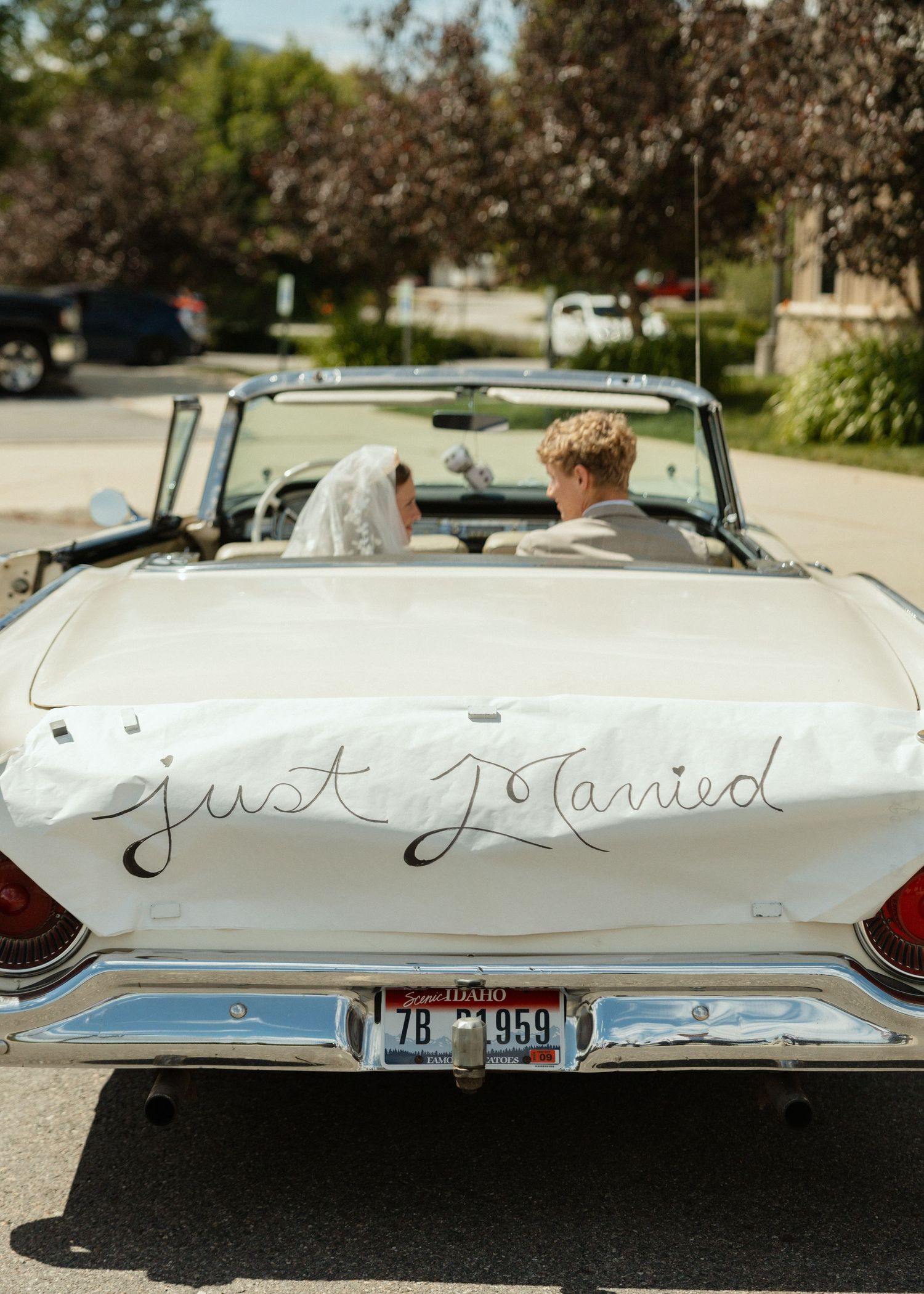 A bride and groom in a vintage convertible with a 