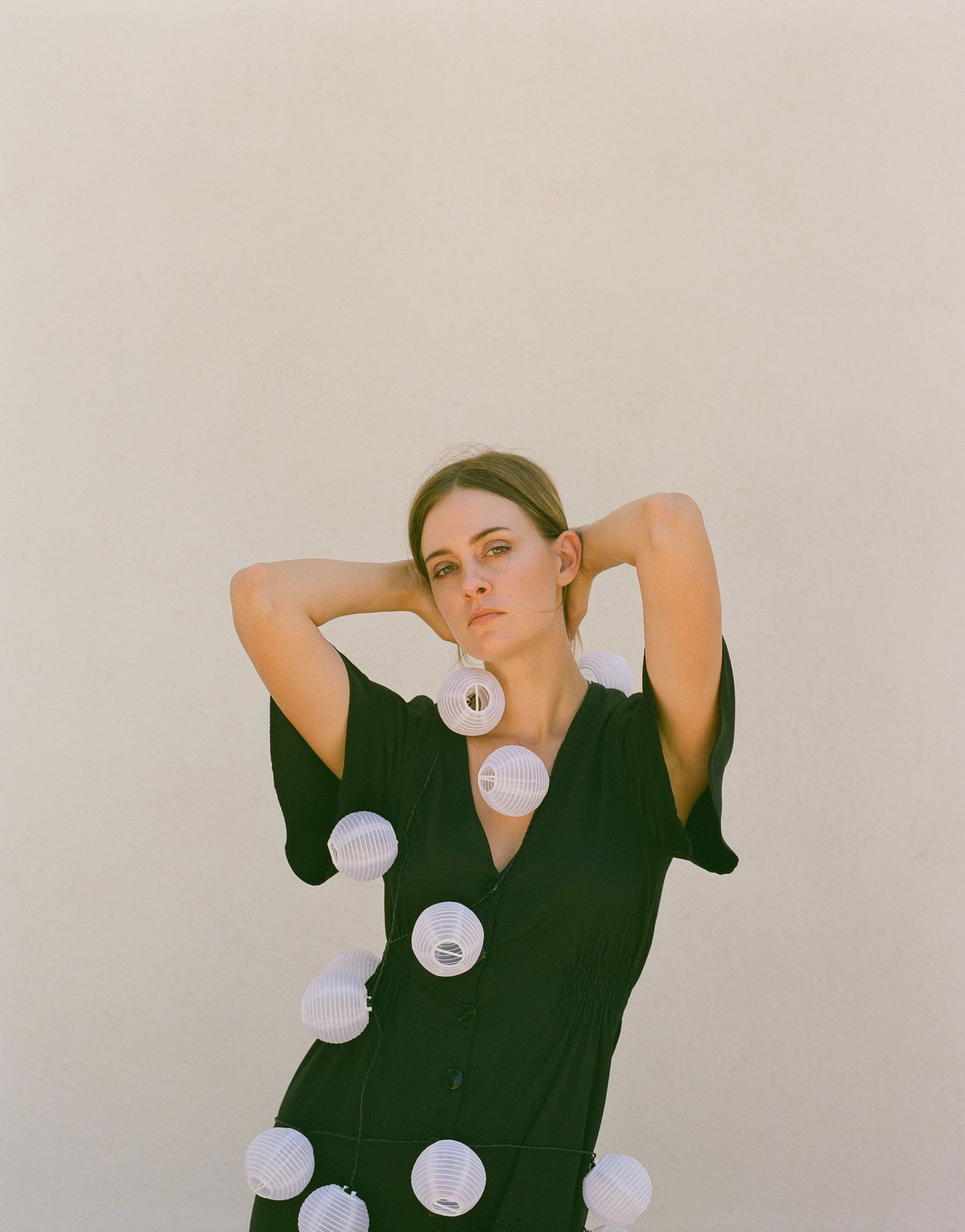A fashion editorial featuring a dark green dress with large white polka dot details.
