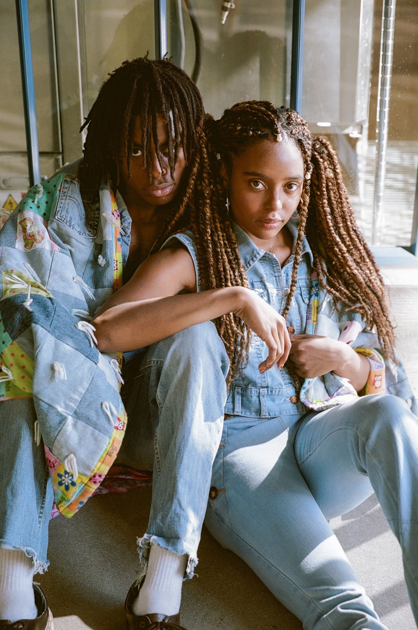 Two people in denim outfits sitting casually together in what appears to be public transit.