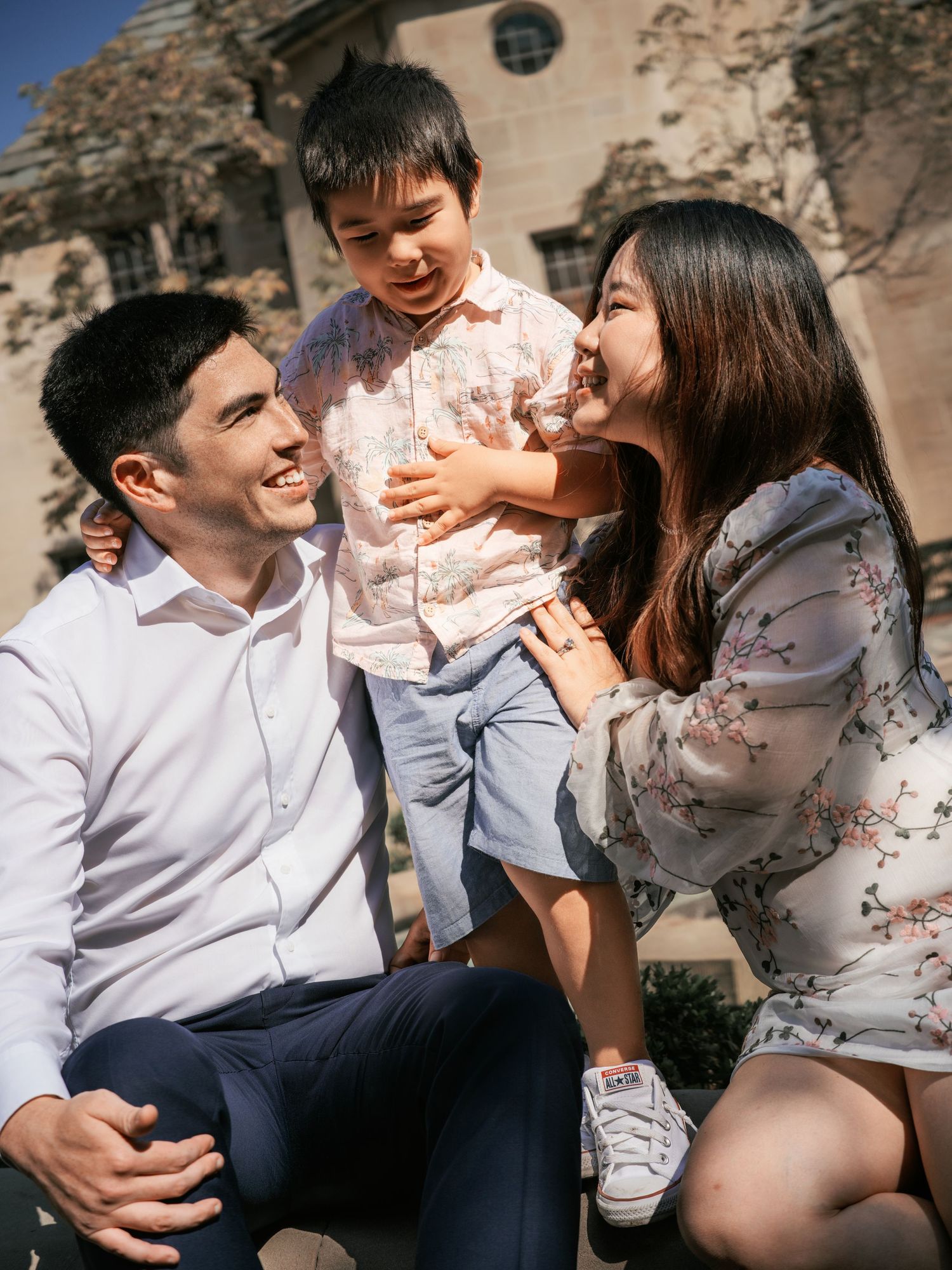 Joyful family moment captured outdoors with stone architecture in background.