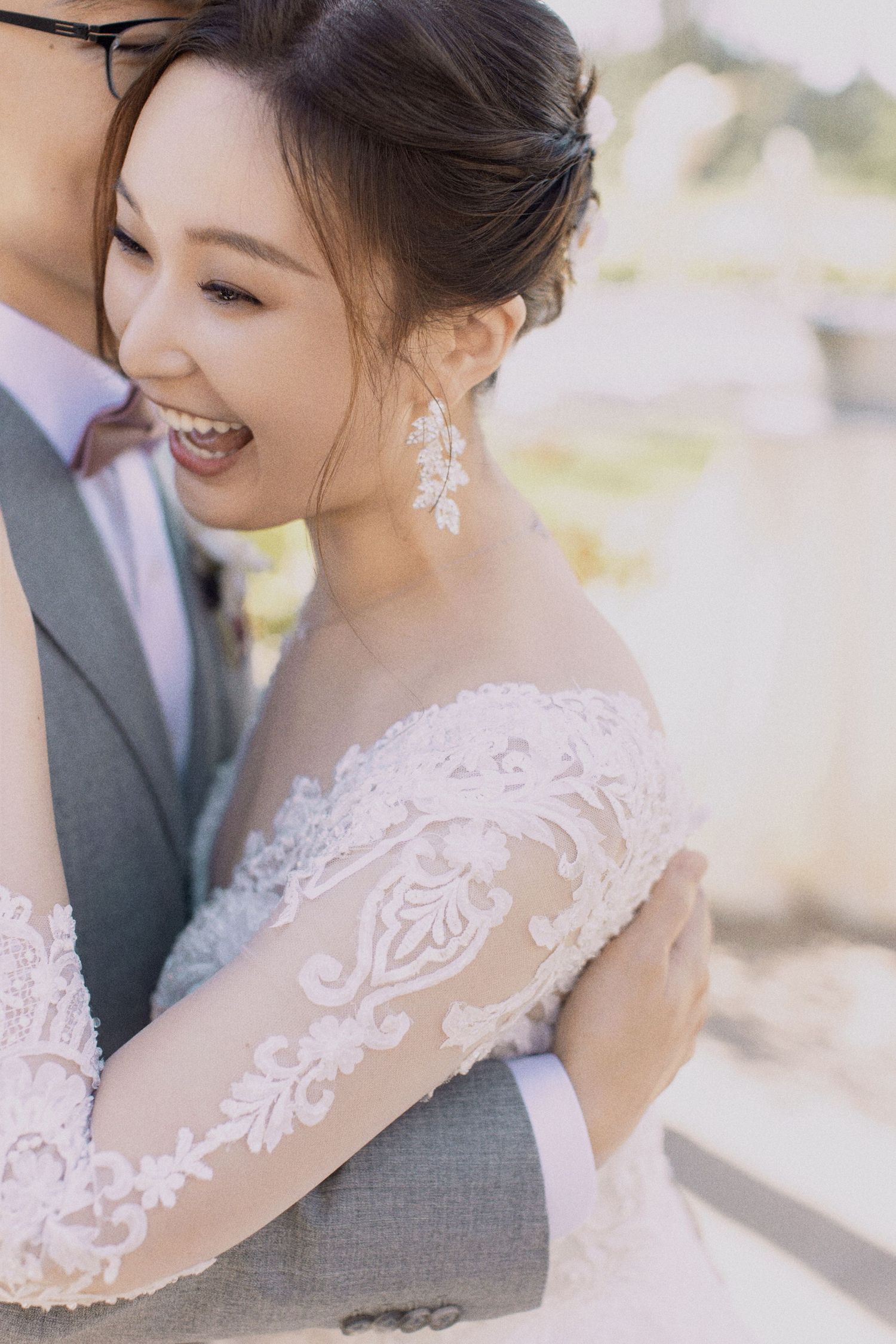 Joyful bride in lace dress laughing during intimate wedding portrait.