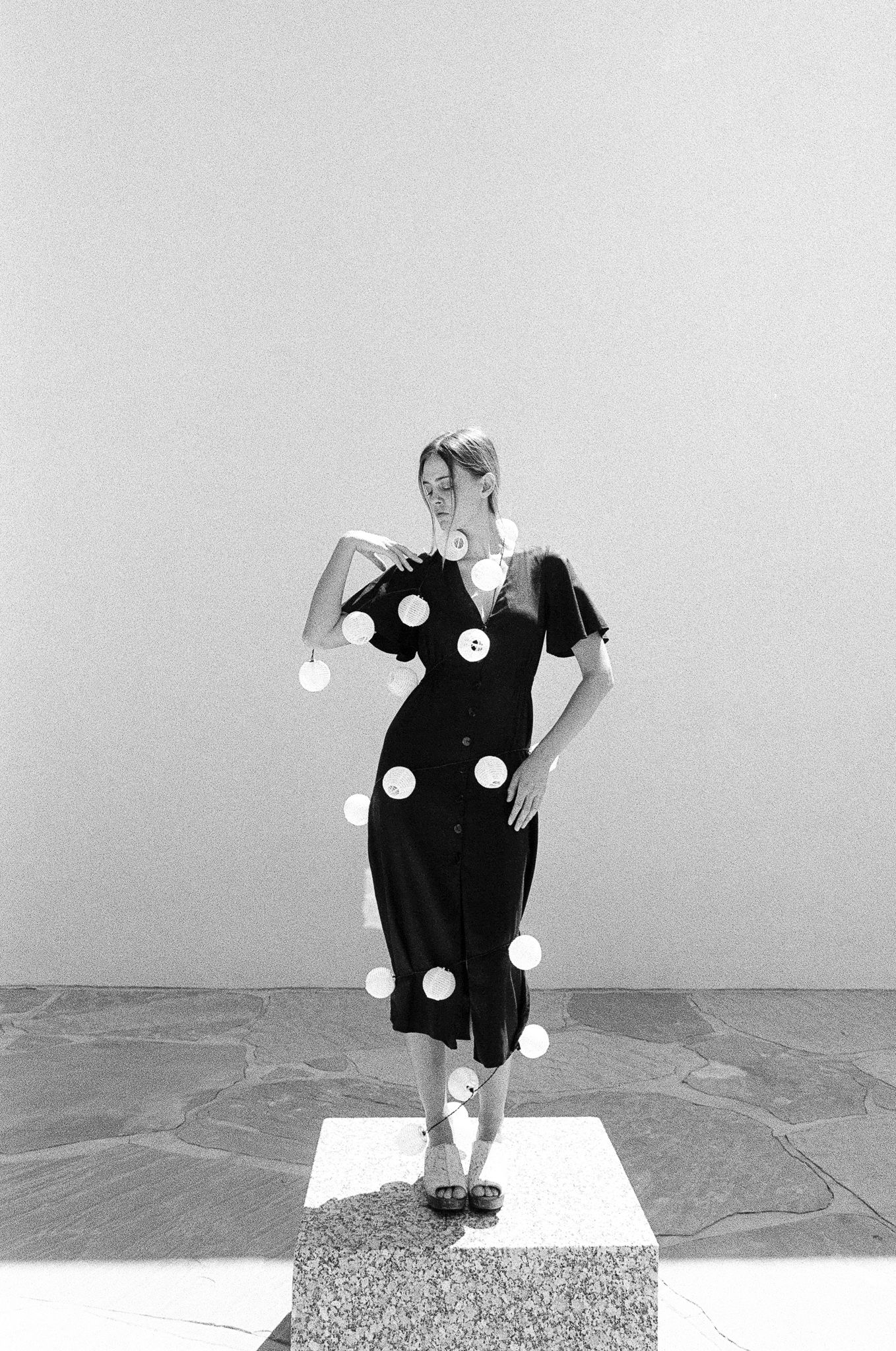 Black and white photo of a polka dot dress against minimalist backdrop.
