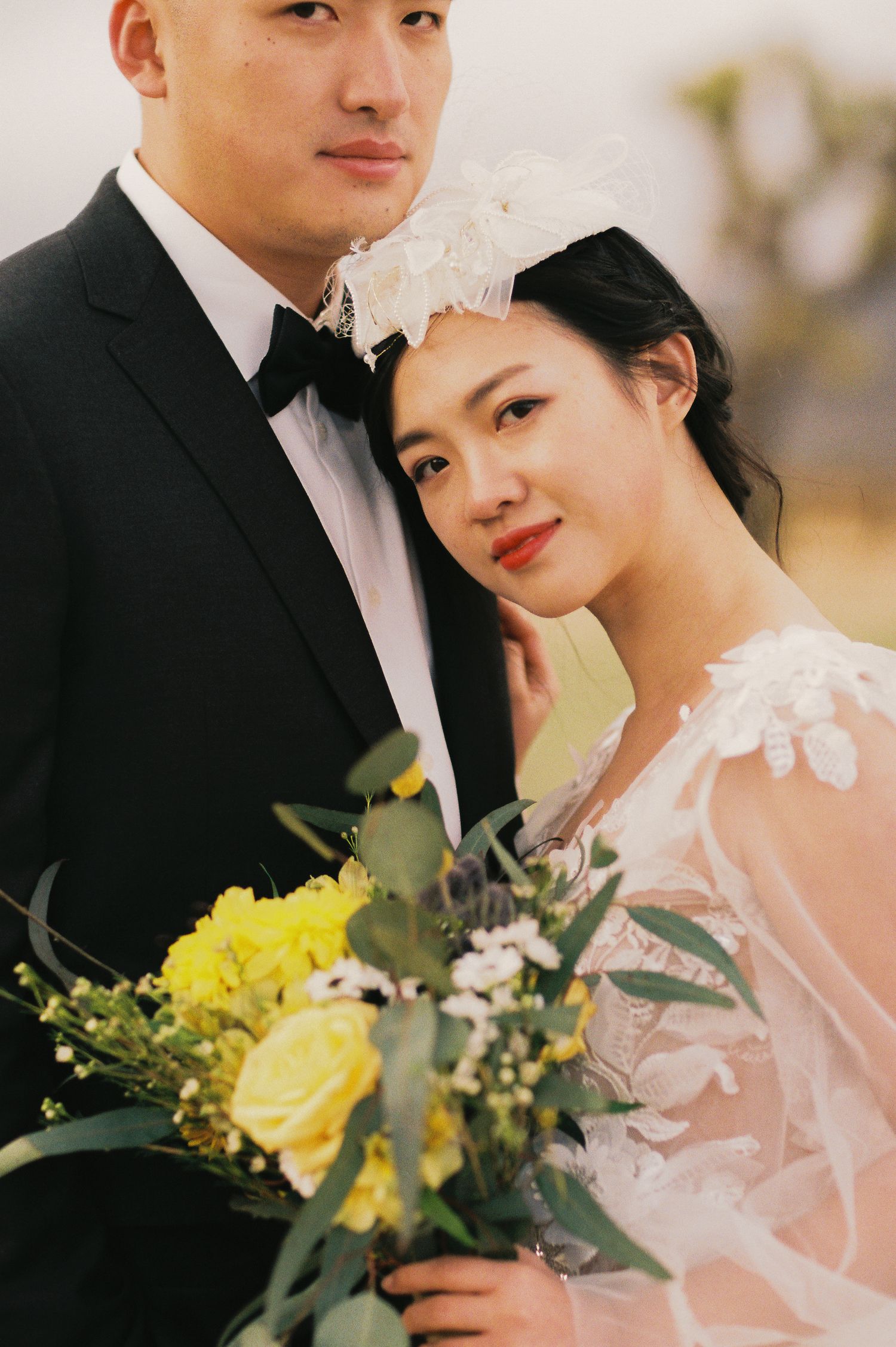 An elegant wedding portrait featuring a yellow bouquet and delicate lace details.
