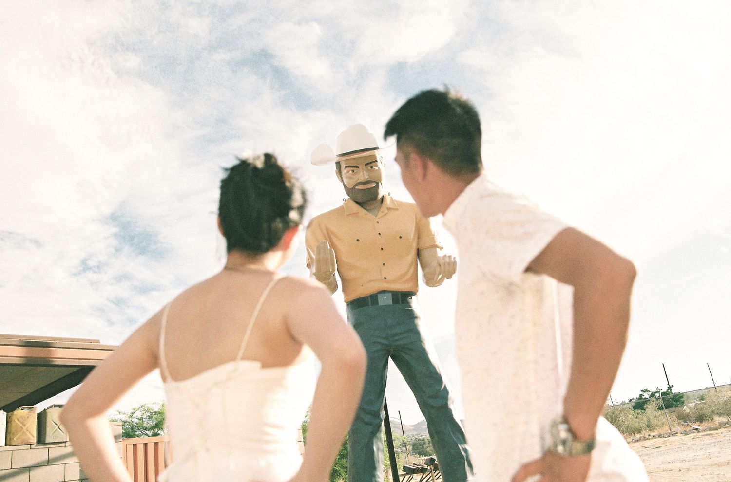 Three people in casual summer attire standing outdoors in a desert landscape under cloudy skies.