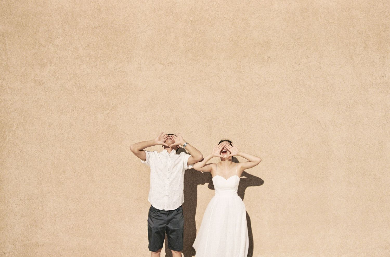 Playful pose against beige wall in casual summer attire.