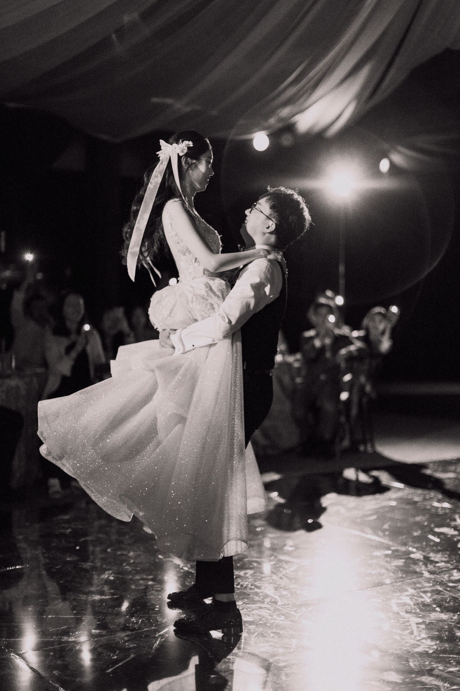 A romantic black and white photo of newlyweds dancing with a dramatic lift.