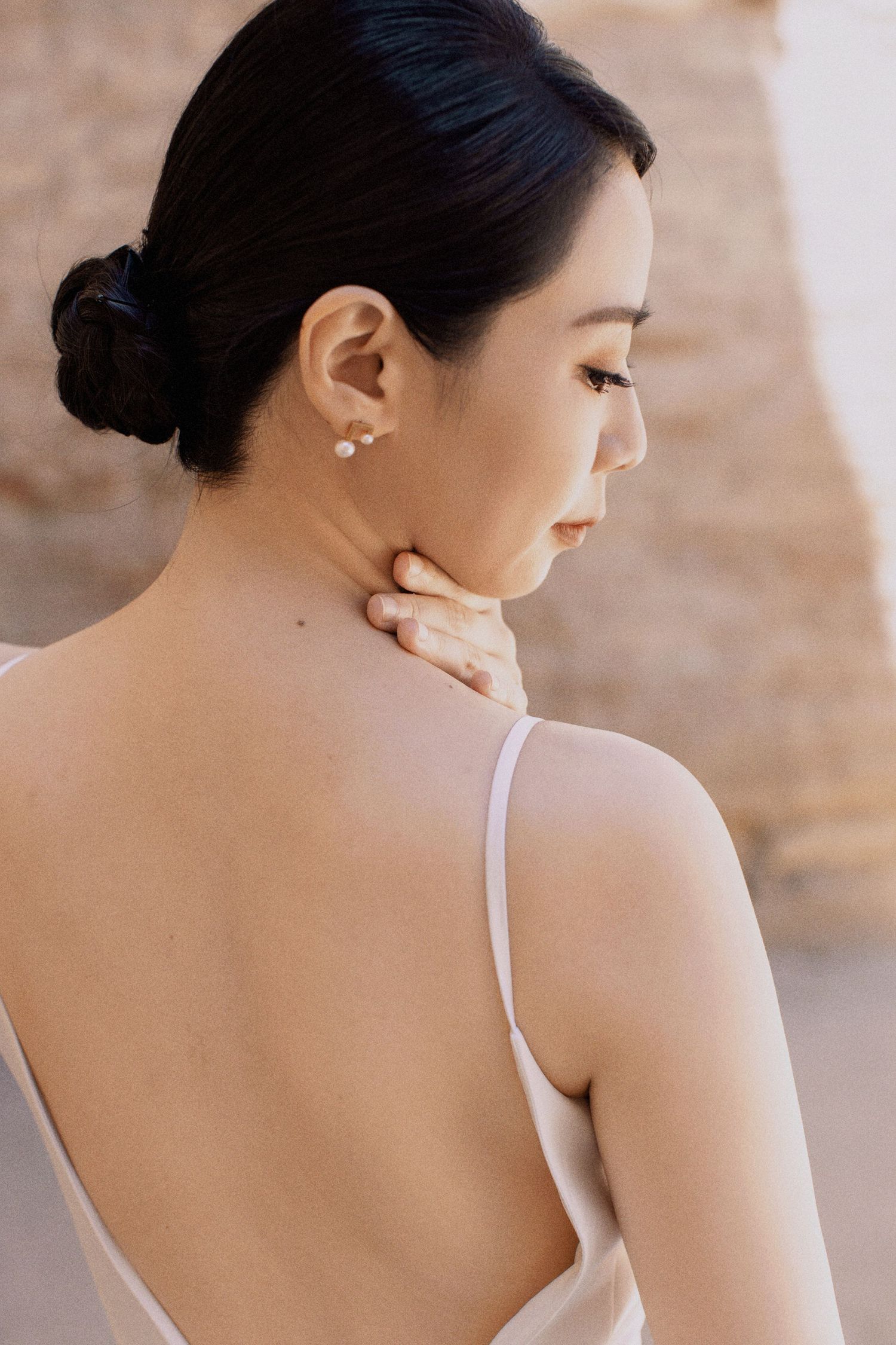 Elegant backside portrait showing delicate spaghetti strap dress and pearl earring.